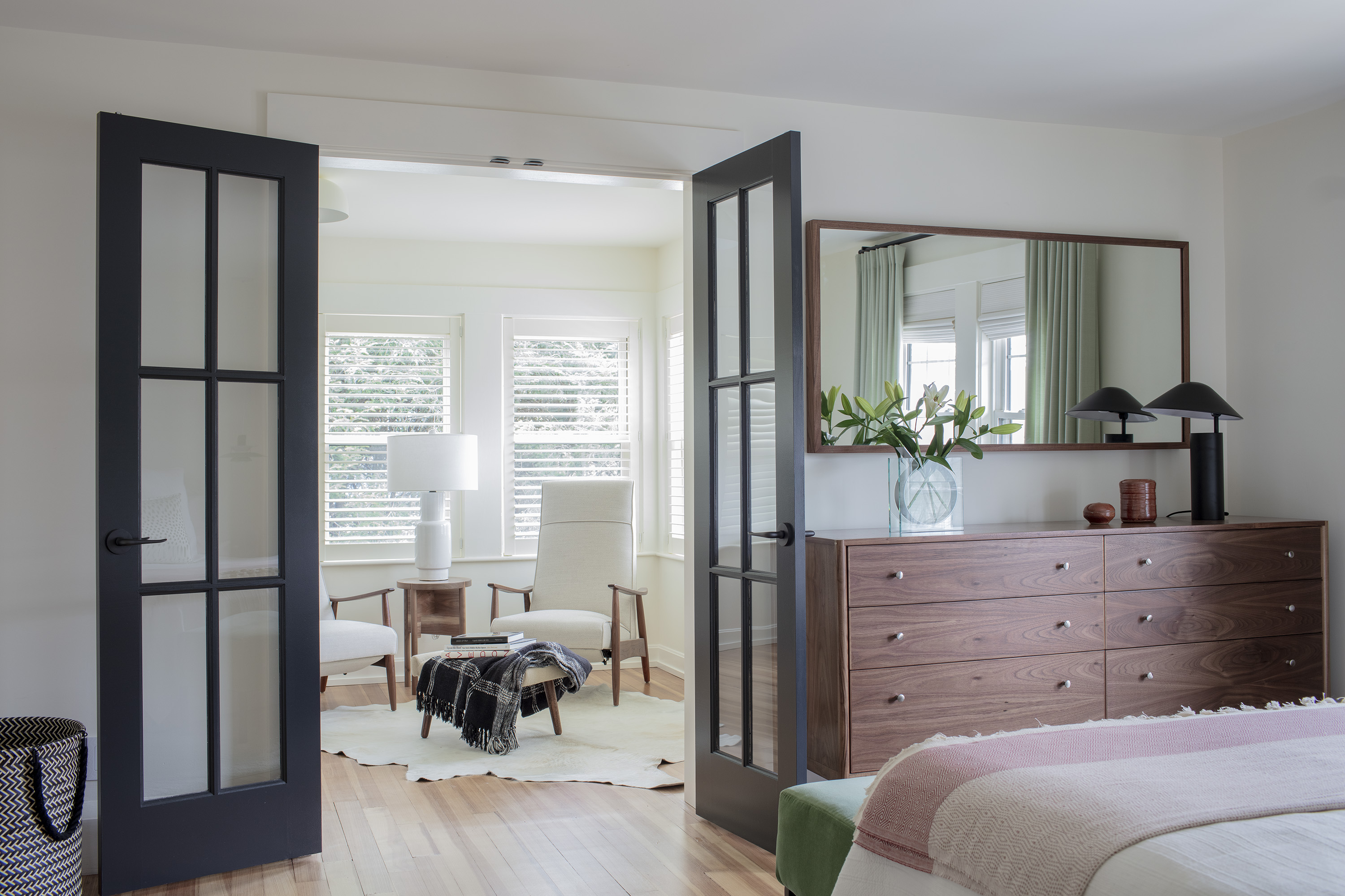 Artful Edge Framing in Allston framed the mirror in walnut to match the custom walnut dresser that Hall designed. Recliners from Design Within Reach flank a custom walnut side table. The new doors leading to the sitting room have black frames for visual interest.