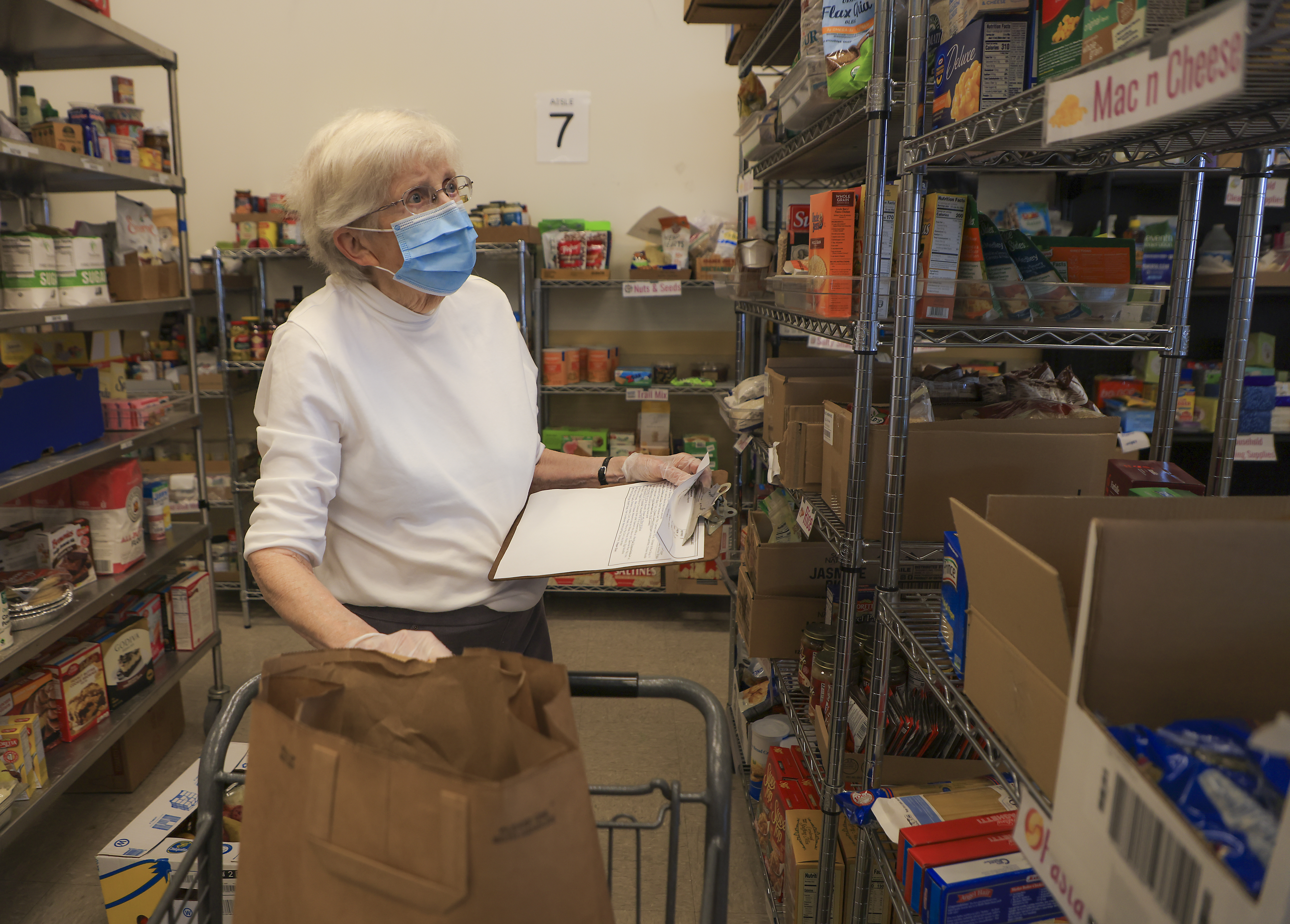 Dr. Nancy Hendrie, 90 a retired pediatrician from Emerson Hospital and volunteer at the Open Table in Maynard, fills a custom shopping bag for a family in need.