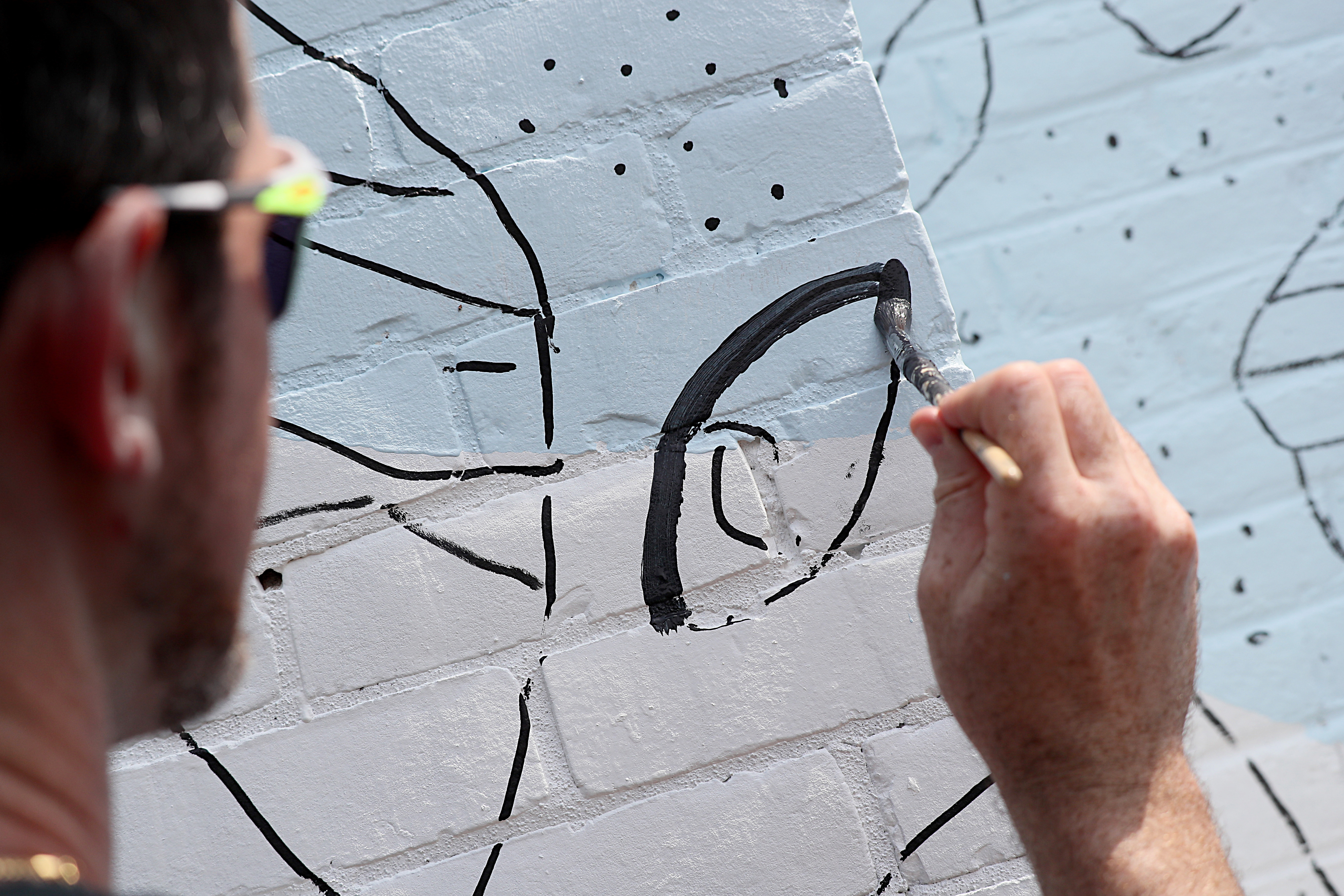 Artist Brian Kenny works on his mural at the Open Door Health clinic.