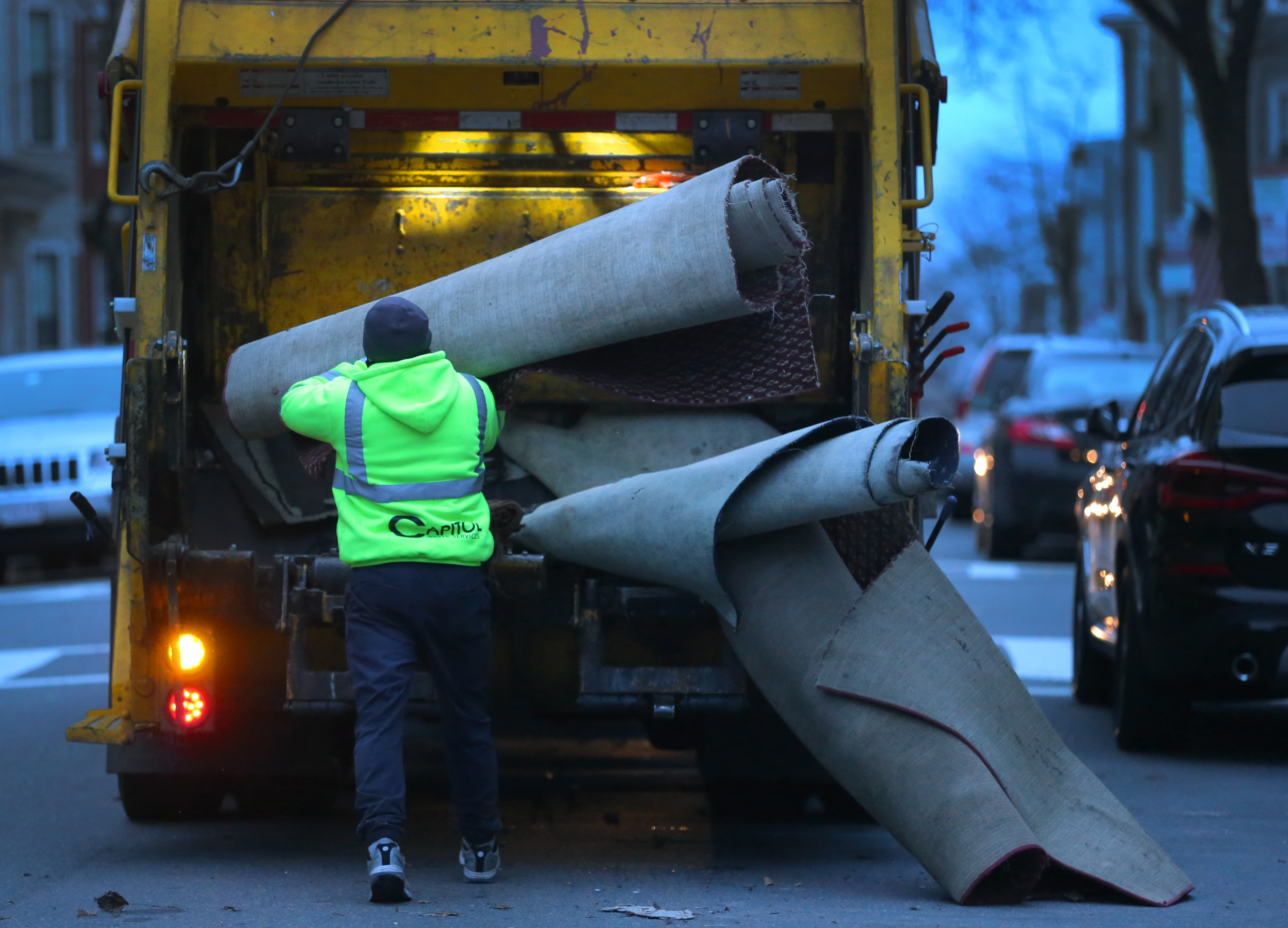 Juan Sandoval stuffed old carpet into the waste collection vehicle in South Boston on Tuesday morning.