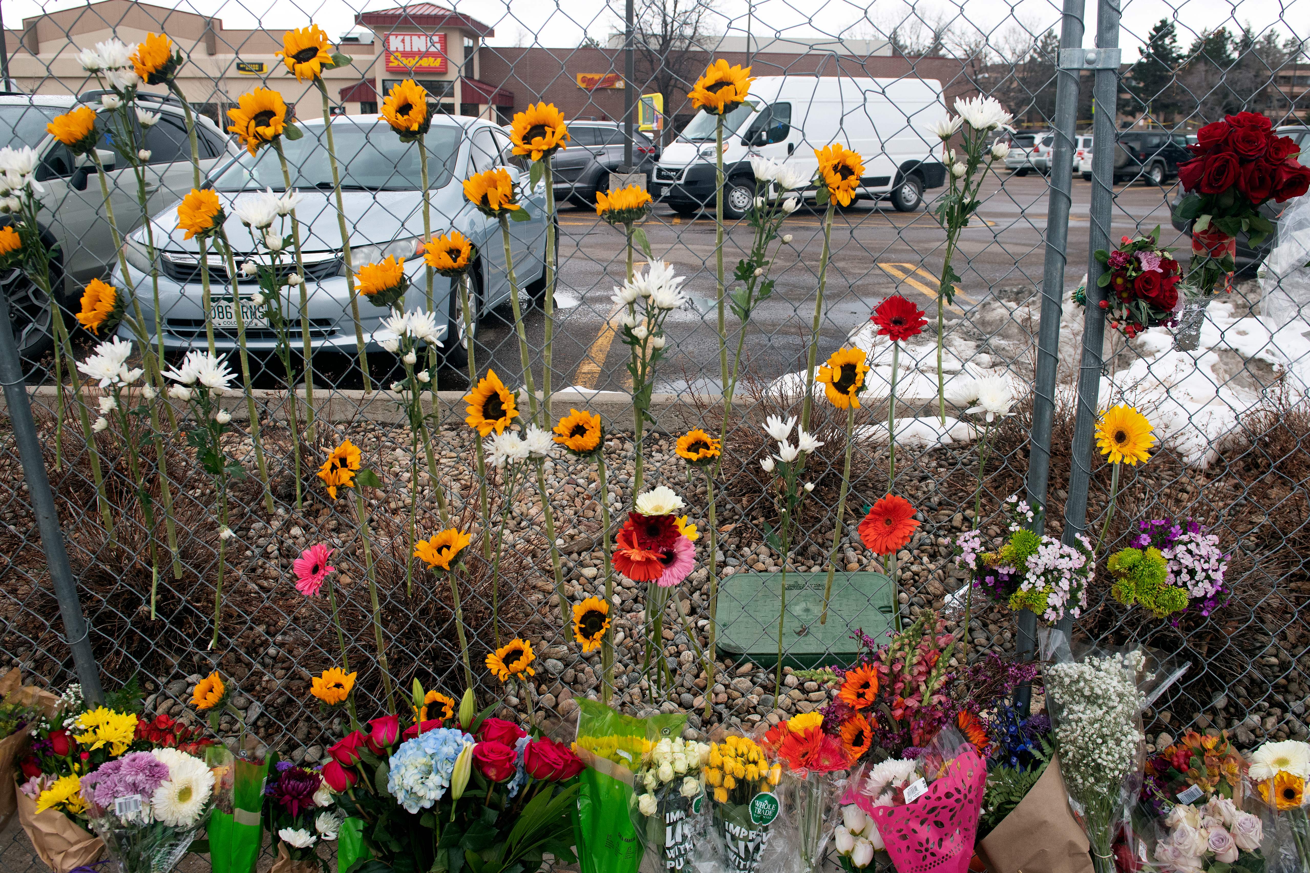 Flowers hang from the perimeter fence outside a King Soopers grocery store in Boulder, Colo.