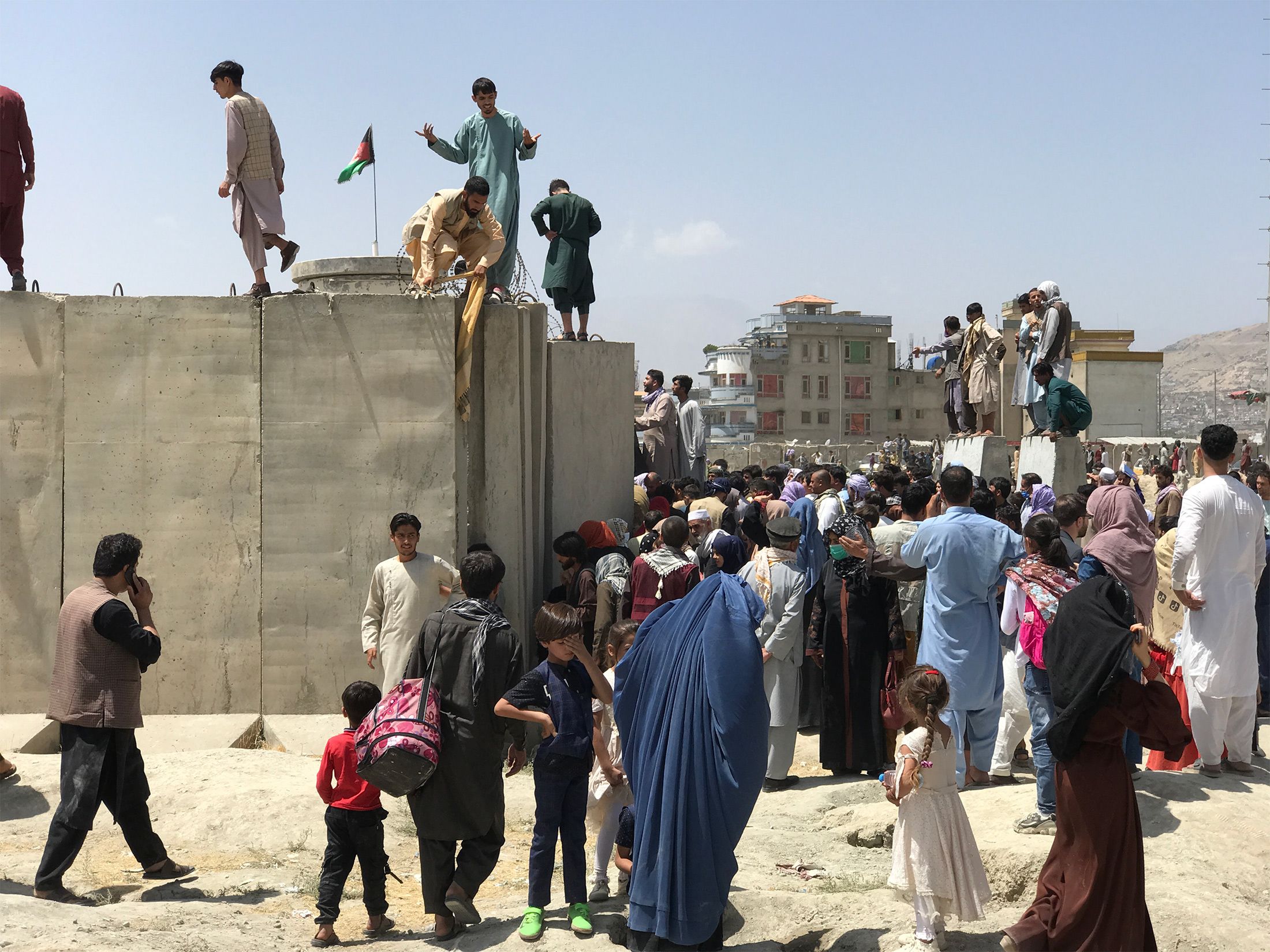 Afghanis tried to cross the wall around Hamid Karzai International Airport to flee the country on Monday.