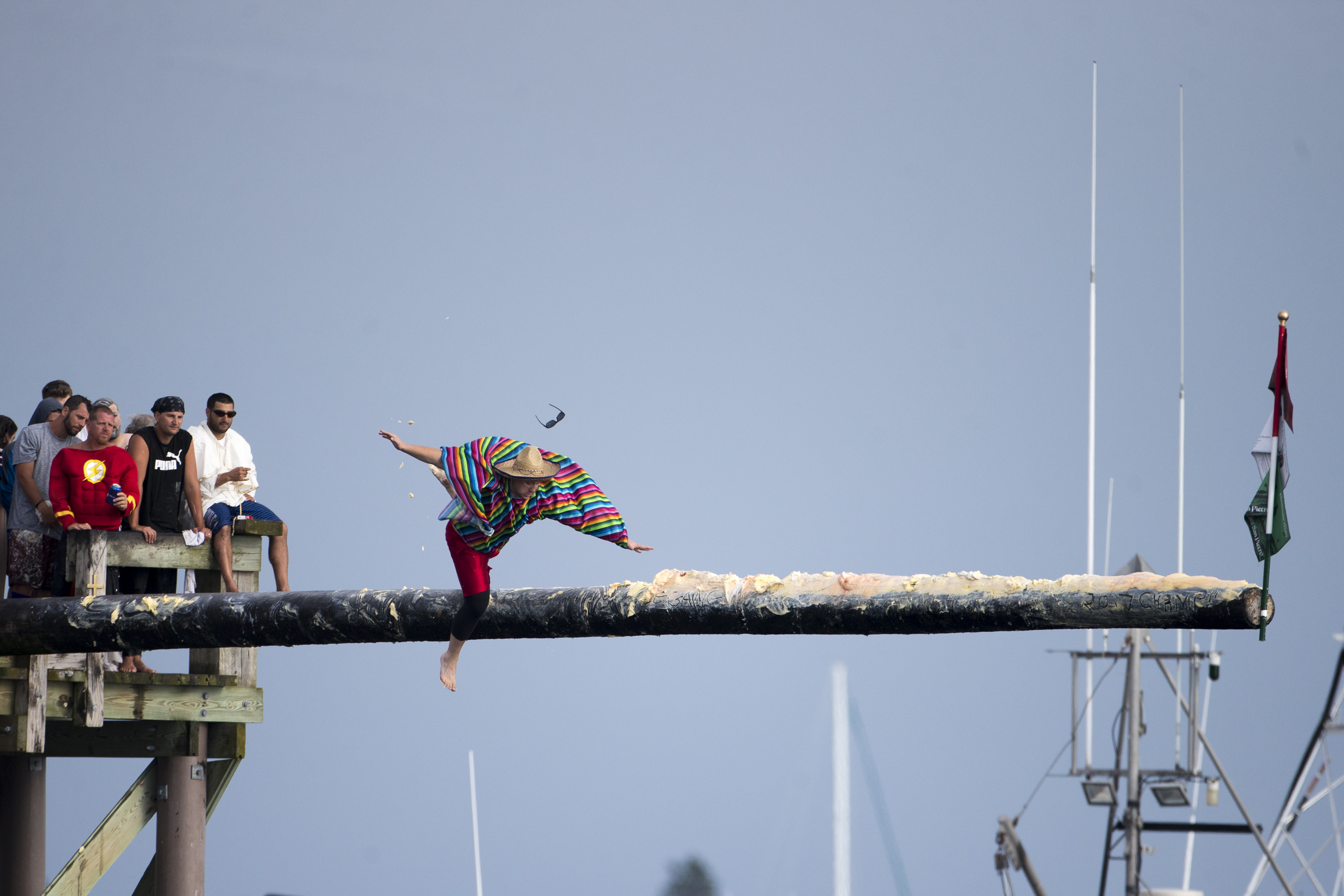 A man slips and falls off the greasy pole during the competition Sunday.