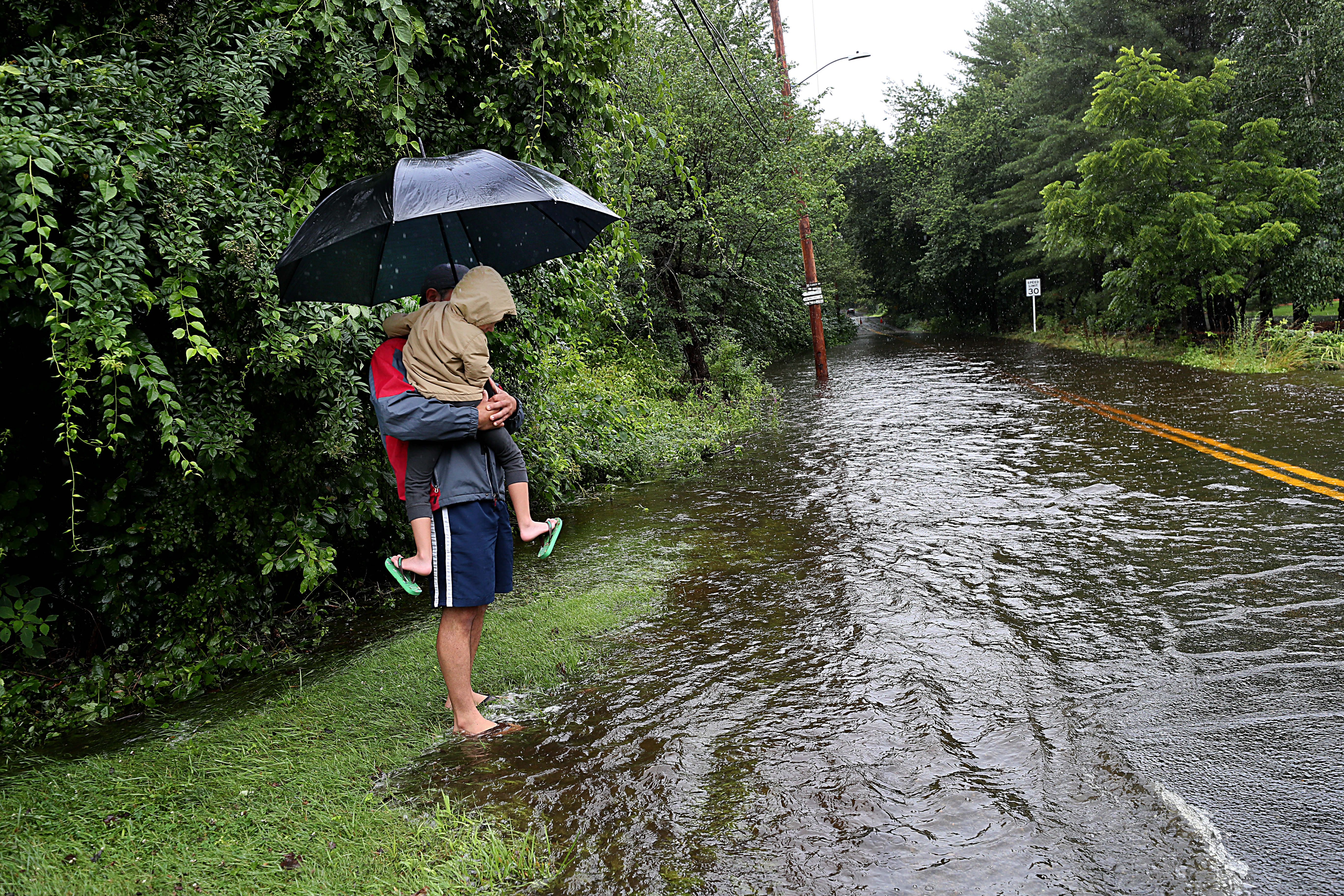 Hebertt Simoes held his 6-year-old son, Nathan, on the flooded street in Framingham on July 9.