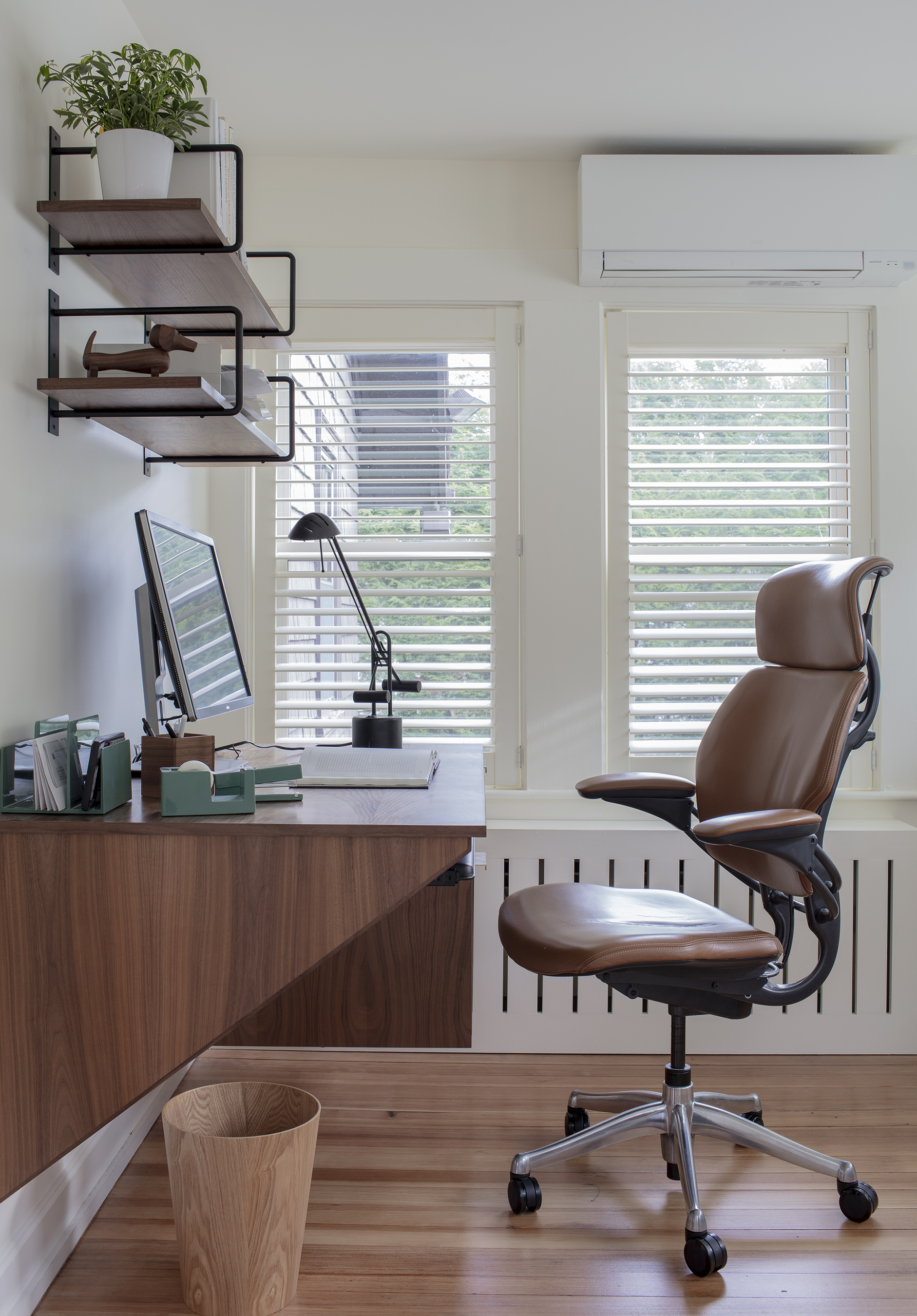 Hall had walnut planks cut for black metal brackets to create shelves above the custom, wall-mounted desk. Timberwolf Construction fabricated the contemporary radiator cover.