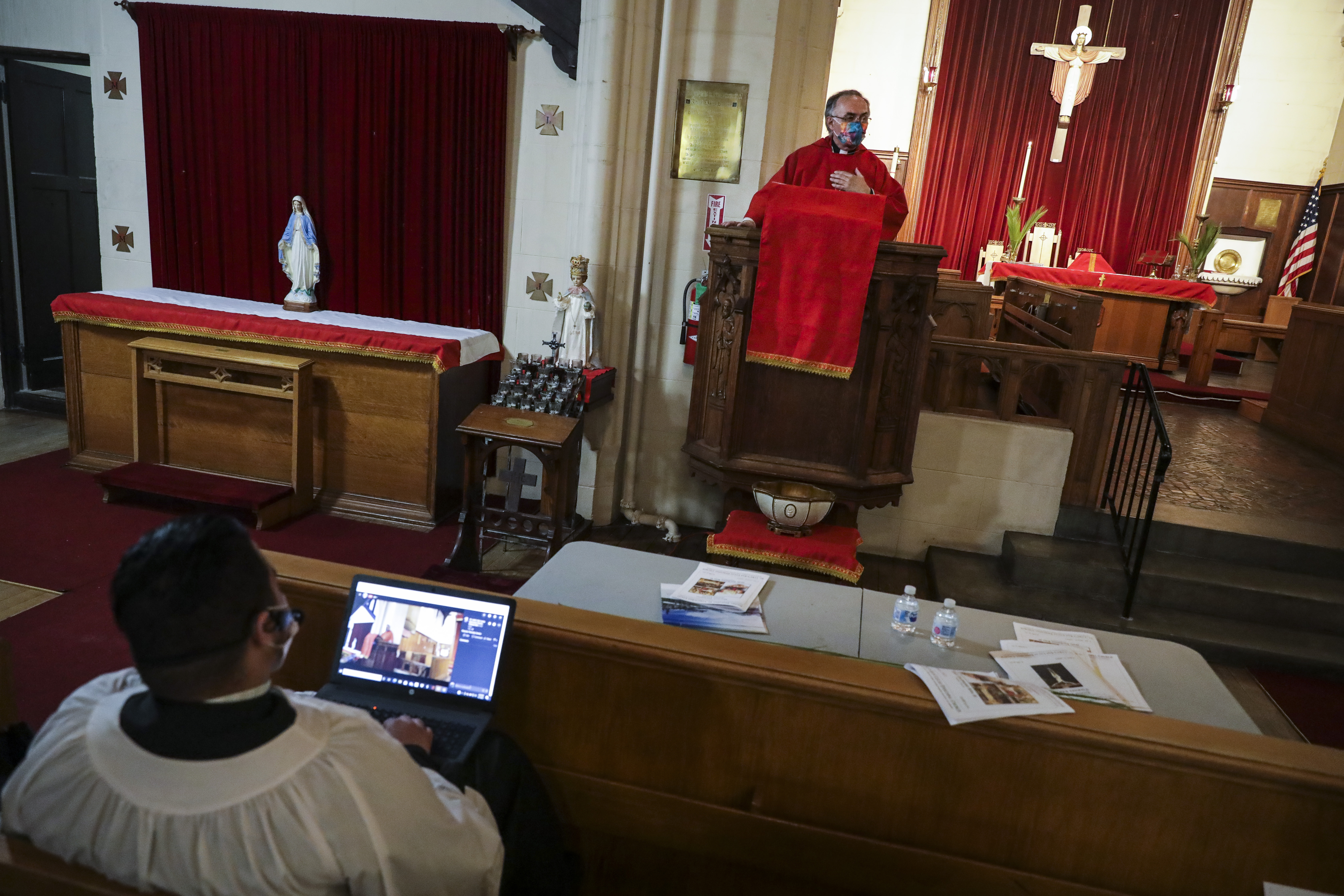 St. Luke-San Lucas Junior Warden Christian DeJesus Franco, left, checked the livestream on his laptop while Rev. Edgar Gutierrez-Duarte delivered the Liturgy of the Word at the service on Maundy Thursday during the Holy Eucharist Rite II.