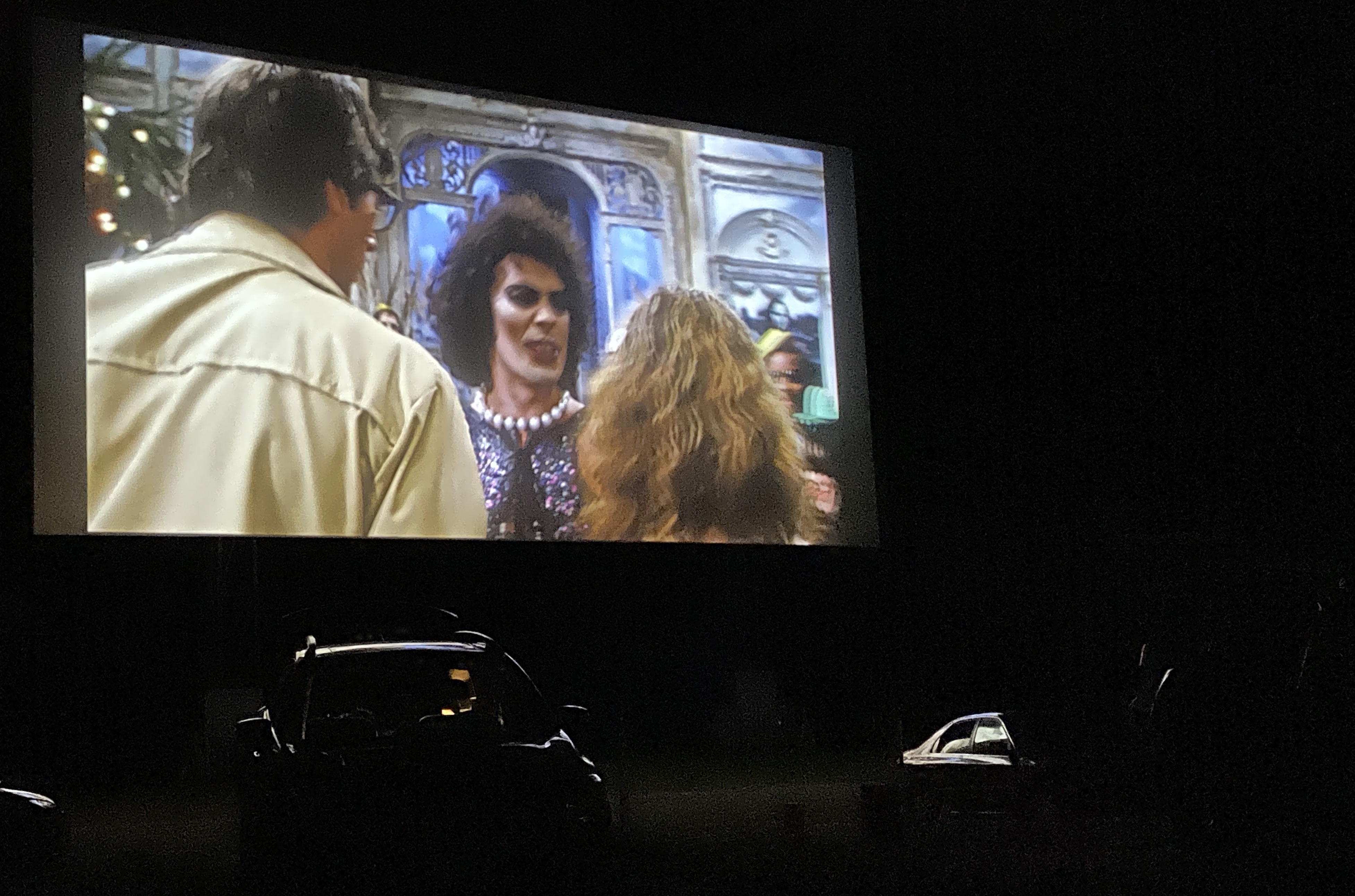 Frank N. Furter (Tim Curry) confronts Janet Weiss (Susan Sarandon) and Brad Majors (Barry Bostwick) in a screening of "The Rocky Picture Show" at the Mendon Twin Drive-In.