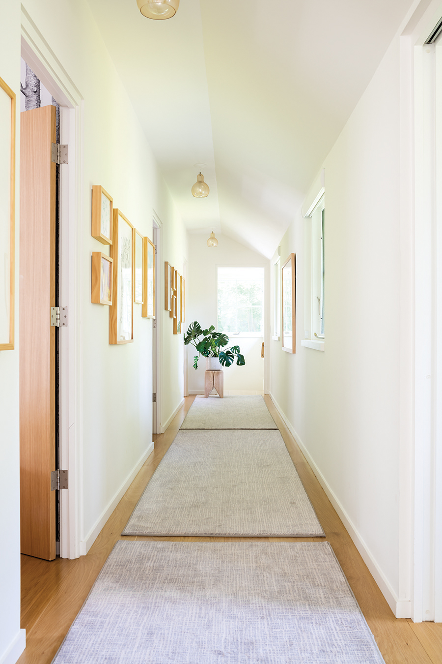 “One long rug can be hard to place, so we used three,” Scales says about her choice for the hallway. The wood stump stool is by Kalon Studios.