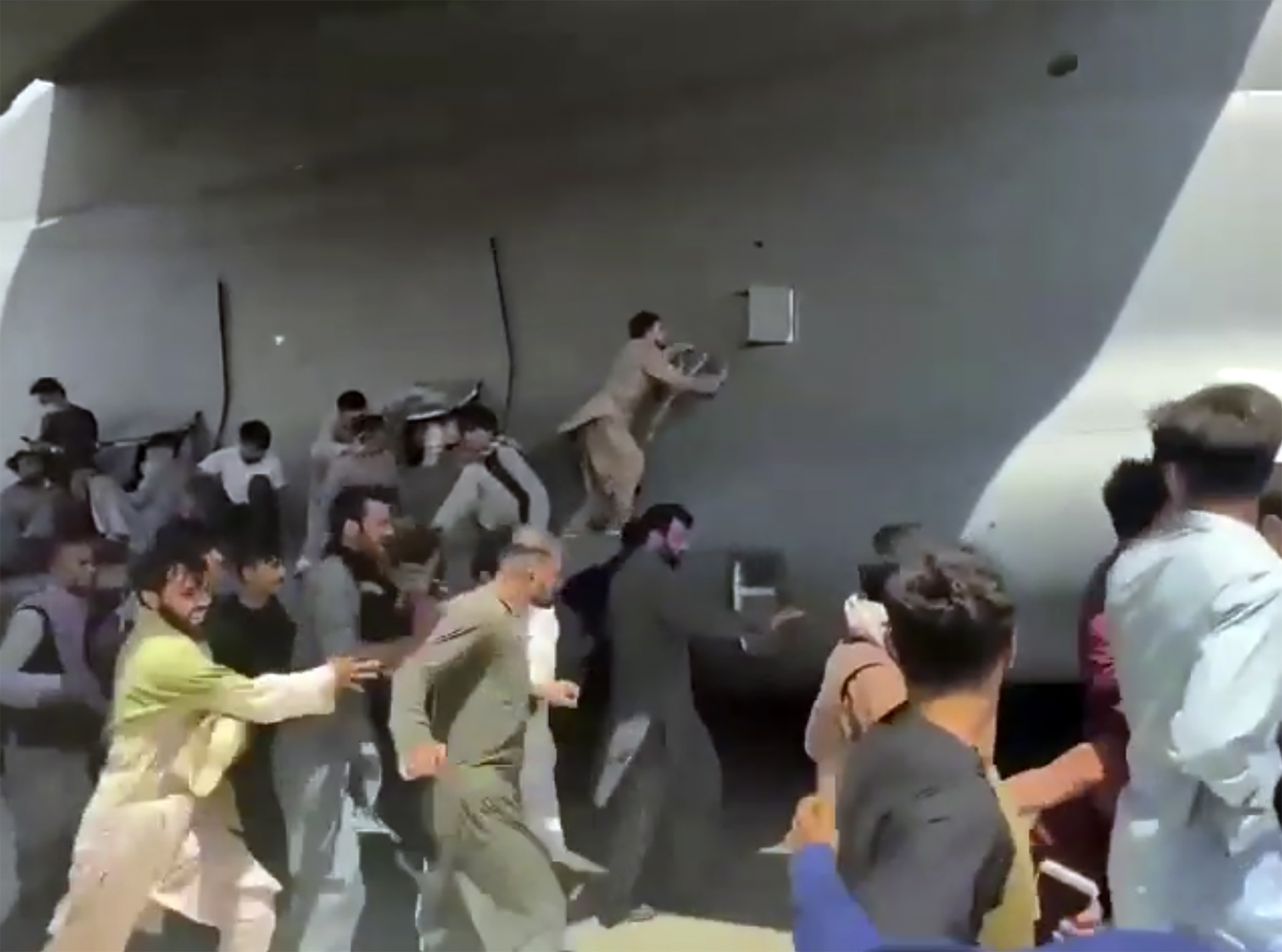Hundreds of people ran alongside a U.S. Air Force C-17 transport plane, some climbing on the plane, as it moved down a runway.