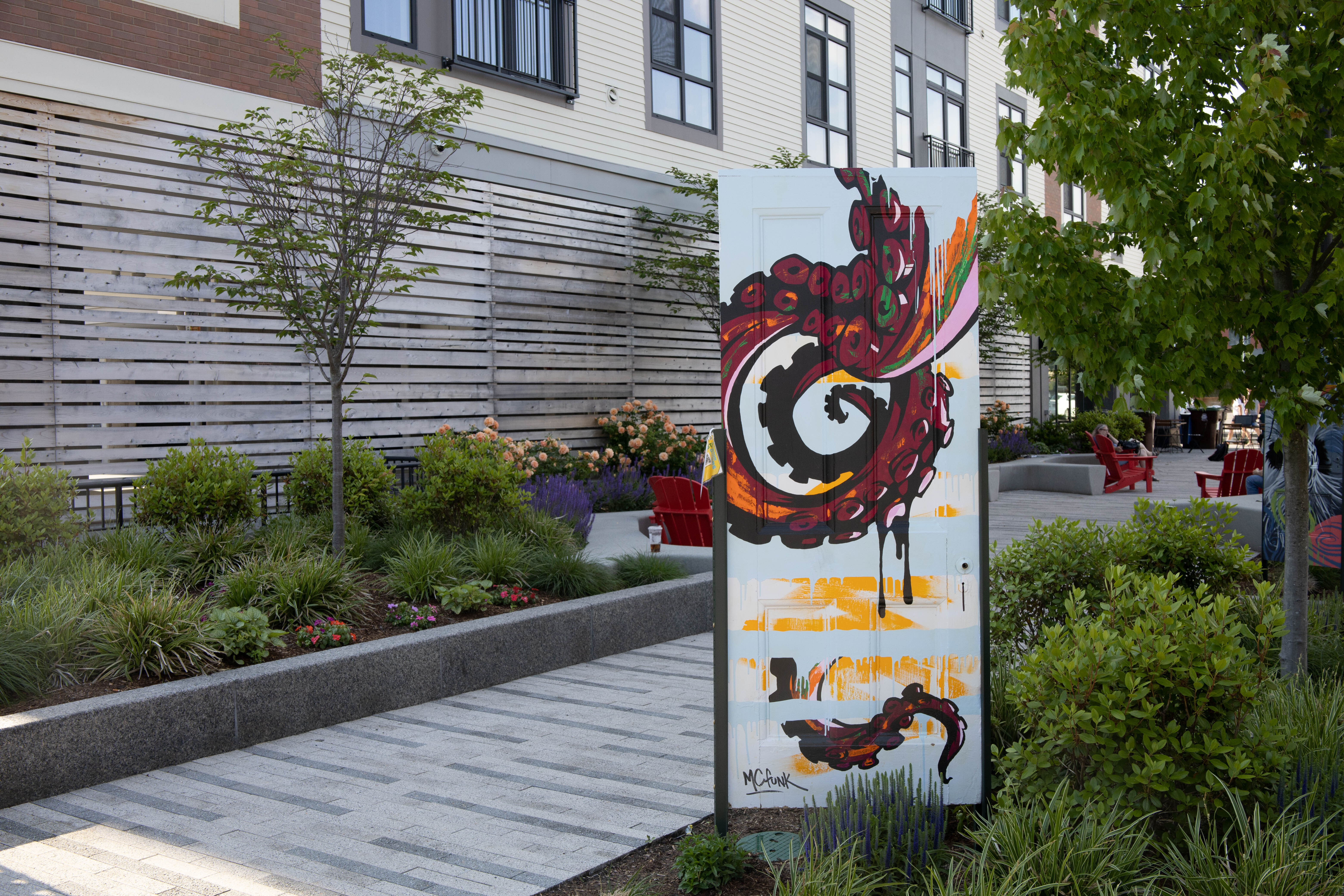 An art project called "Newton Out Doors" features 25 painted doors including "Contact" by Eric Funk. 