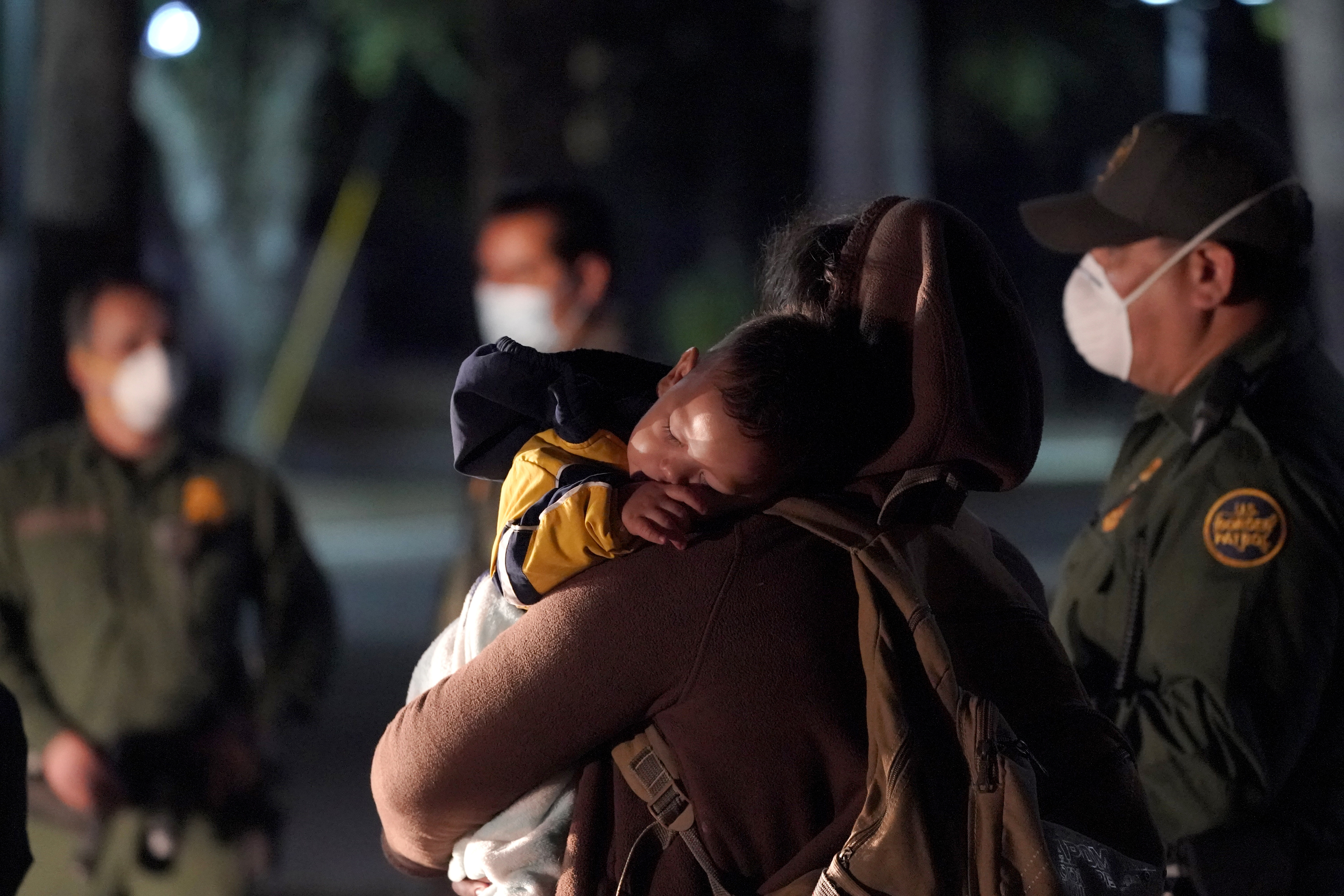 A migrant child sleeps on the shoulder of a woman at an intake area after turning themselves in upon crossing the U.S.-Mexico border early Wednesday in Roma, Texas.