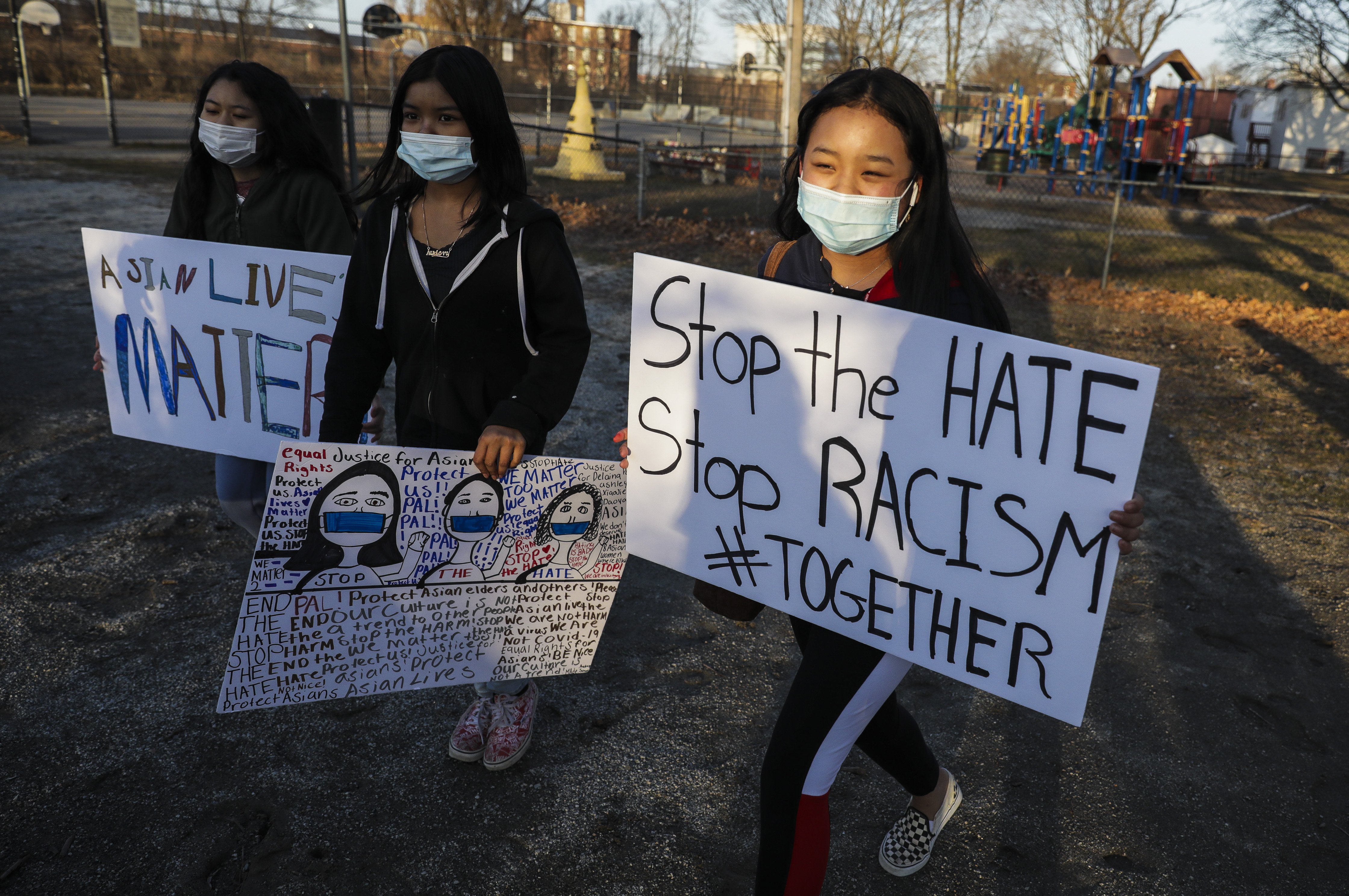 Children carry "stop the hate" and "Asian lives matter" as they walked around Clemente Park in Lowell during a candlelight vigil.