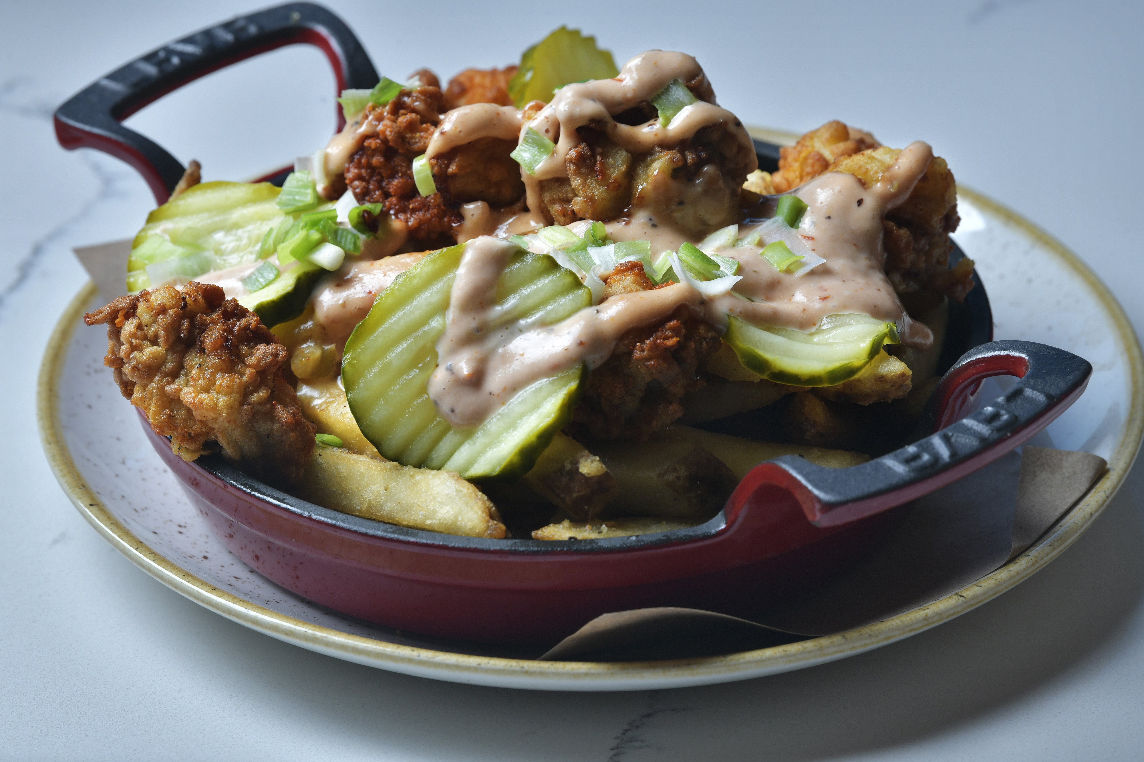 Nashville alligator fries, topped with fried alligator, pickles, pimento queso, and comeback sauce at Buttermilk & Bourbon in Watertown.