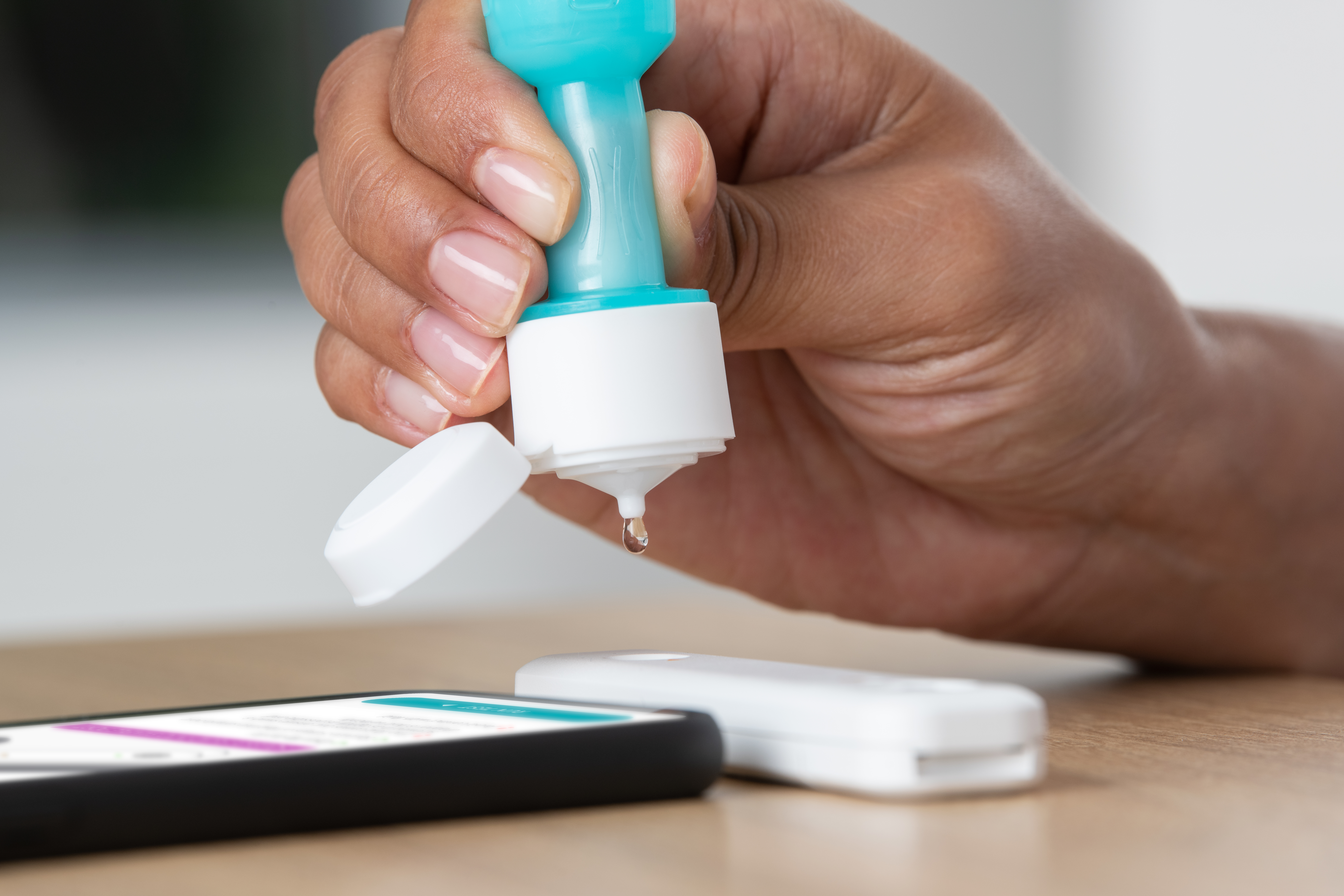 In this image provided by the company, a user puts five drops of fluid into the analyzer, which then sends the test result to the smartphone.