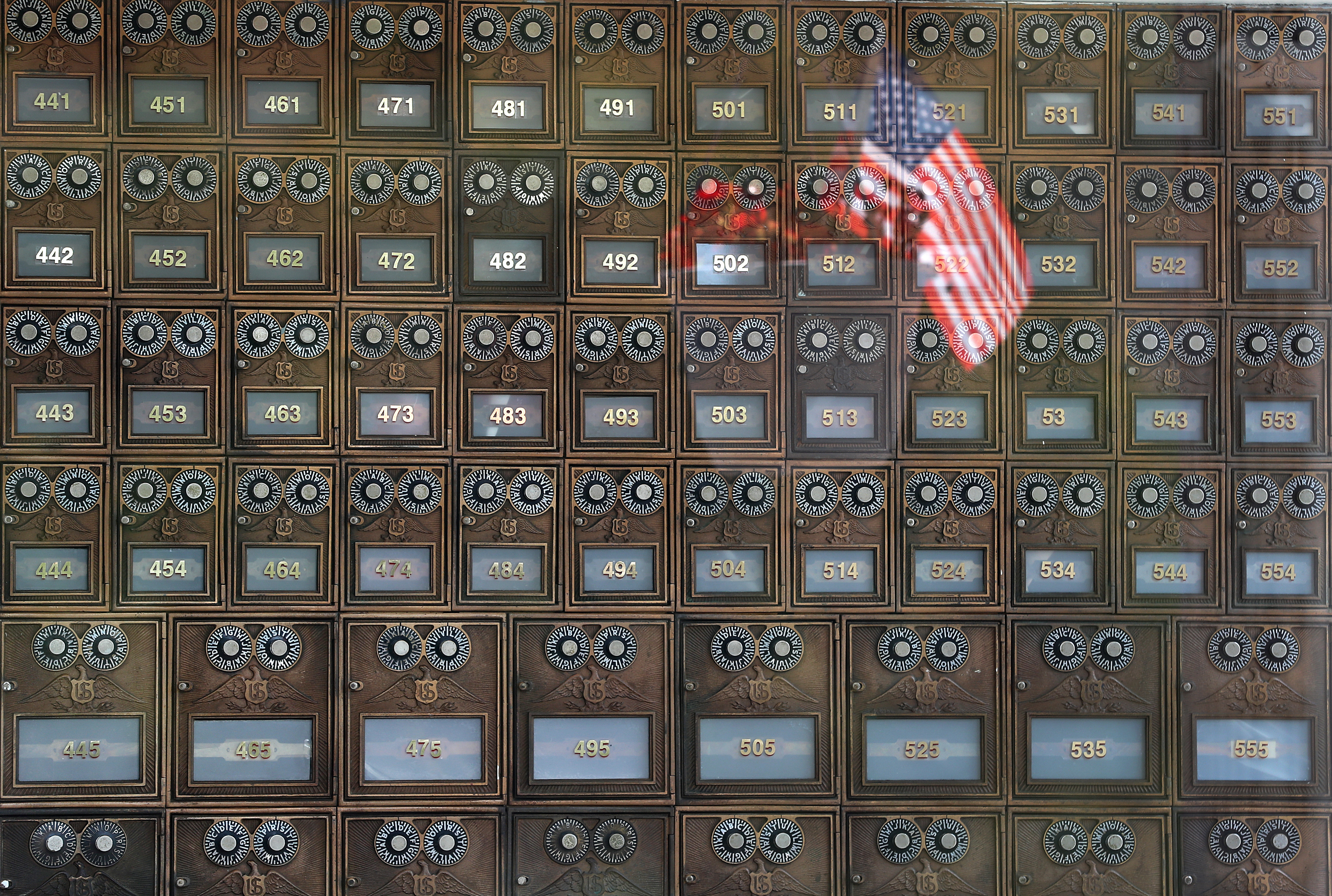 Many residents still come to pick up their mail at the historic post office in North Pembroke. A view of the post office boxes shows an American flag reflected in the window.