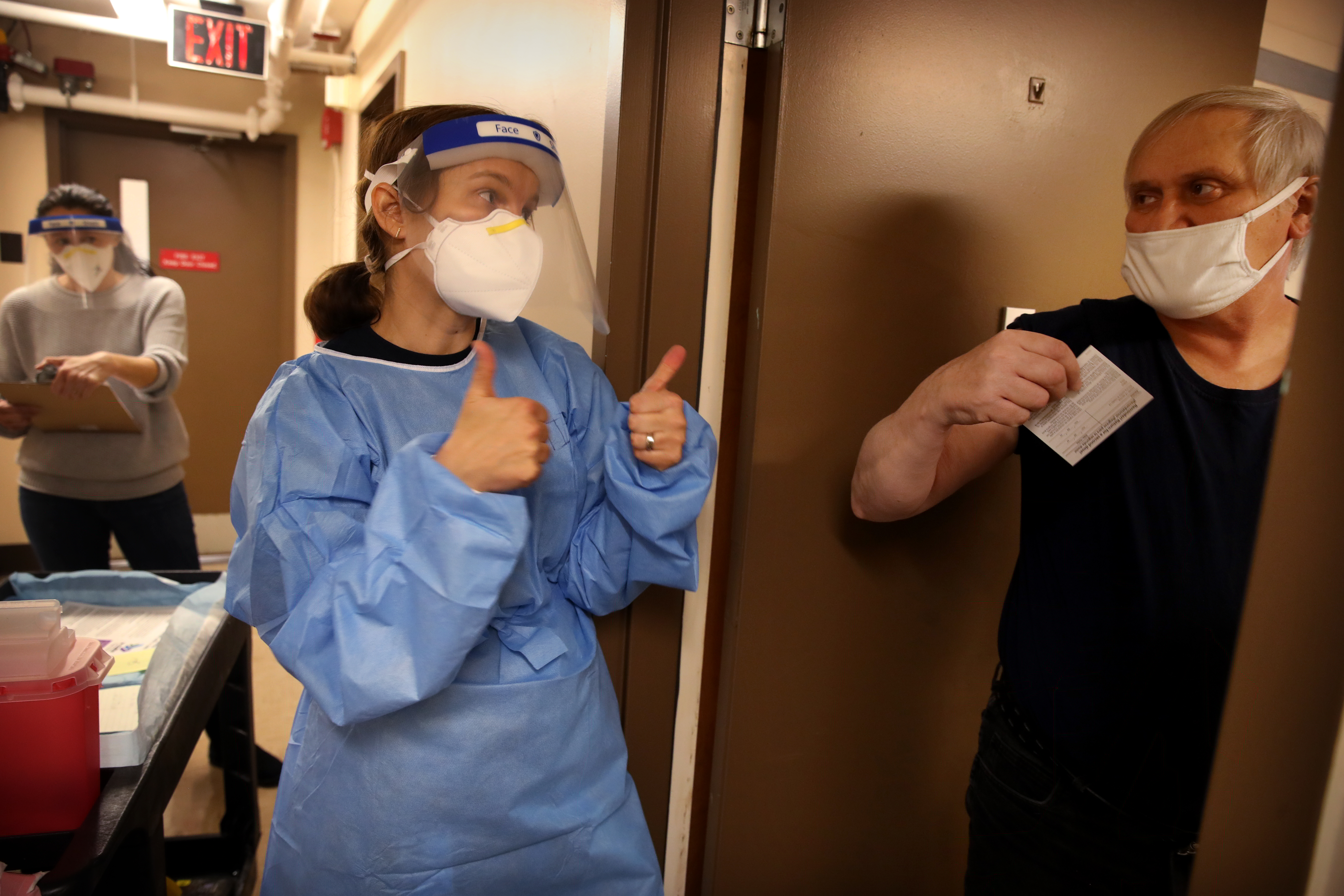 Dr. Katie Fleming offers a double thumbs-up to resident Mike Descote after he received the Moderna COVID-19 Vaccine at his home at Forand Manor in Central Falls, Rhode Island.