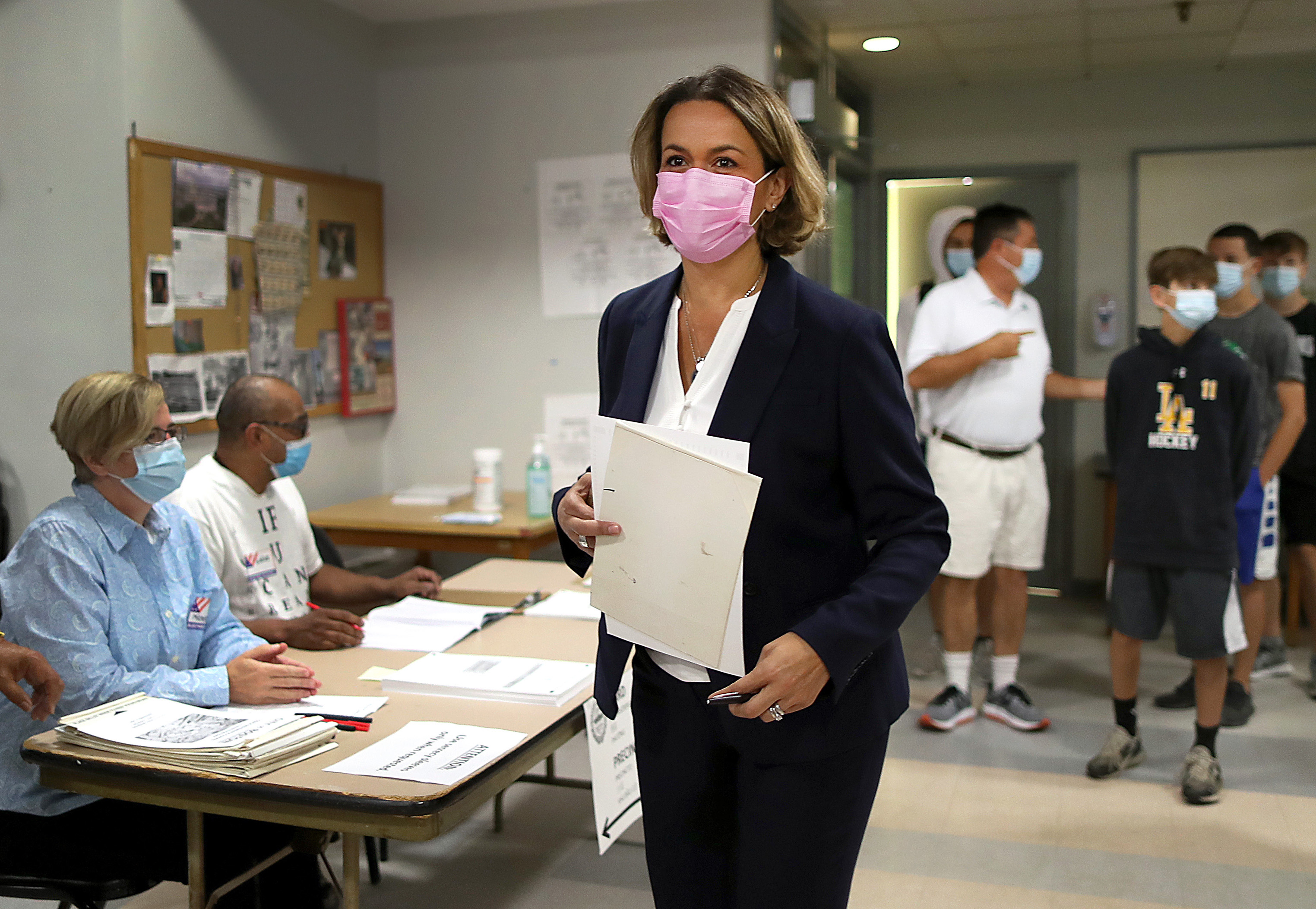Annissa Essaibi George carries her ballot to the booth with her husband, Doug, and sons waiting behind her.