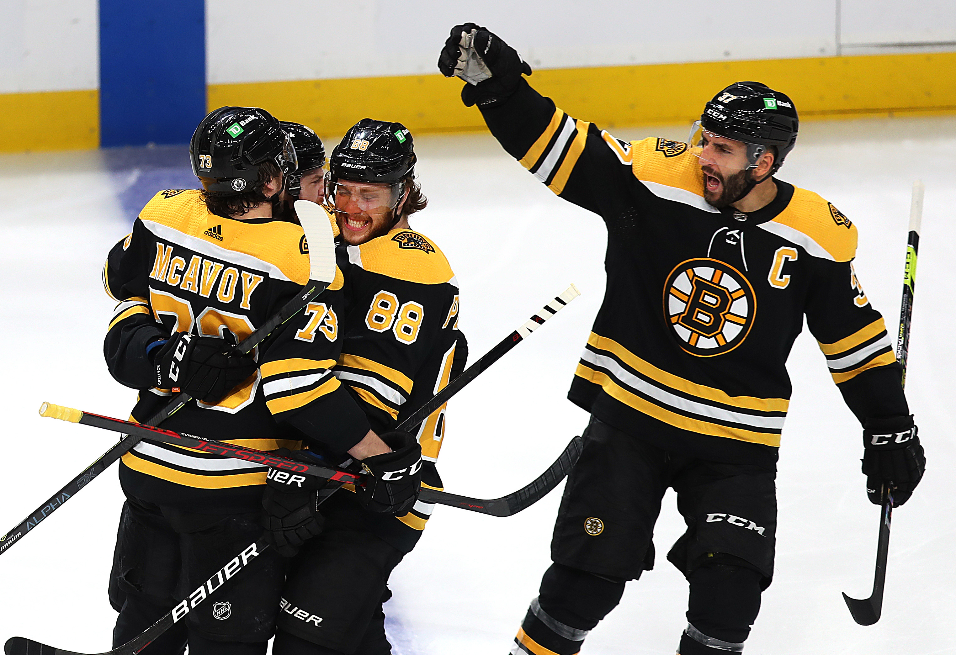 David Pastrnak (center) celebrates his first-period goal with Bruins teammates Charlie McAvoy (left) and Patrice Bergeron.