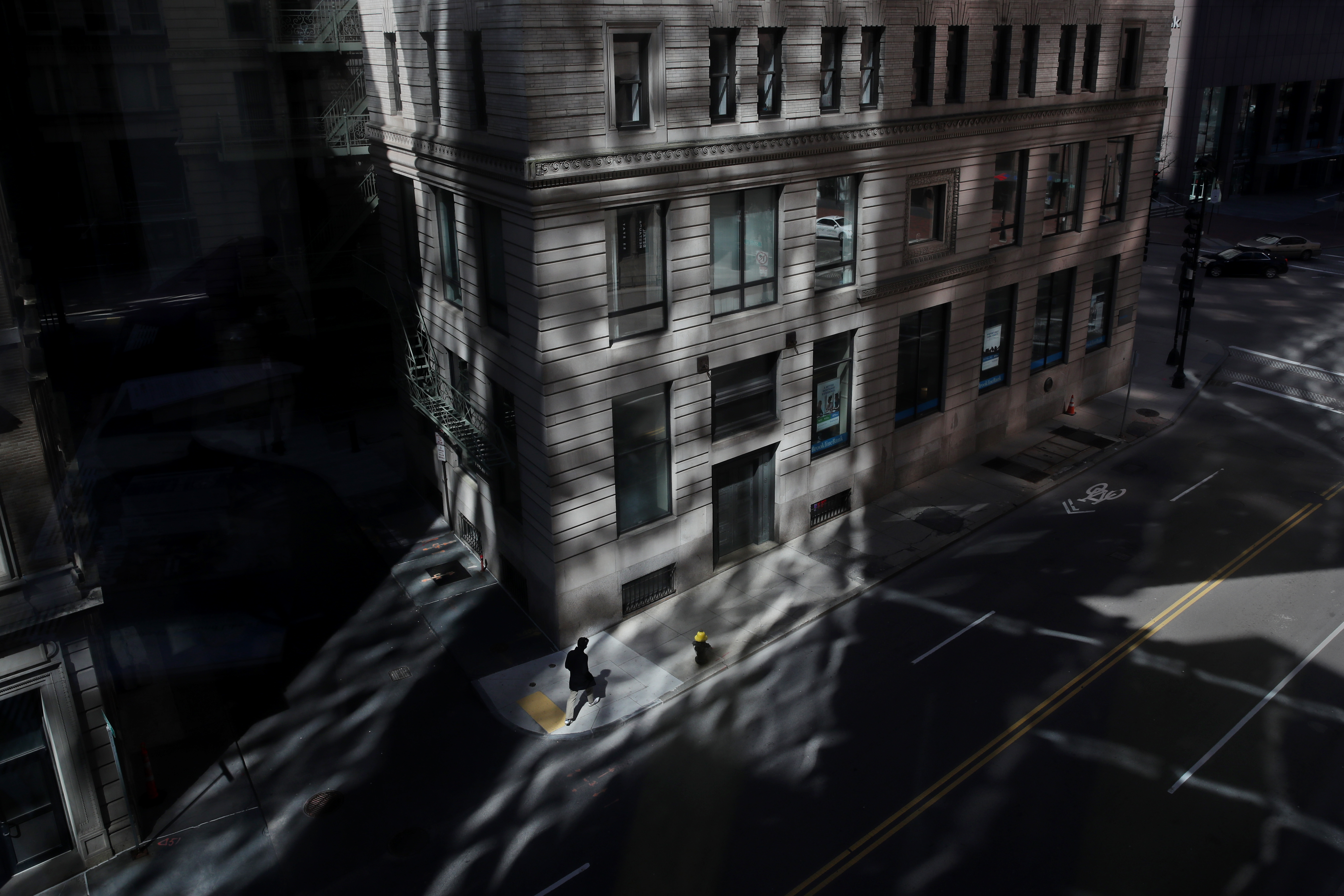 Boston, MA - 3/26/2020: A man passes through reflected light on a near empty Congress Street in downtown Boston, MA on March 26, 2020.  (Craig F. Walker/Globe Staff) 