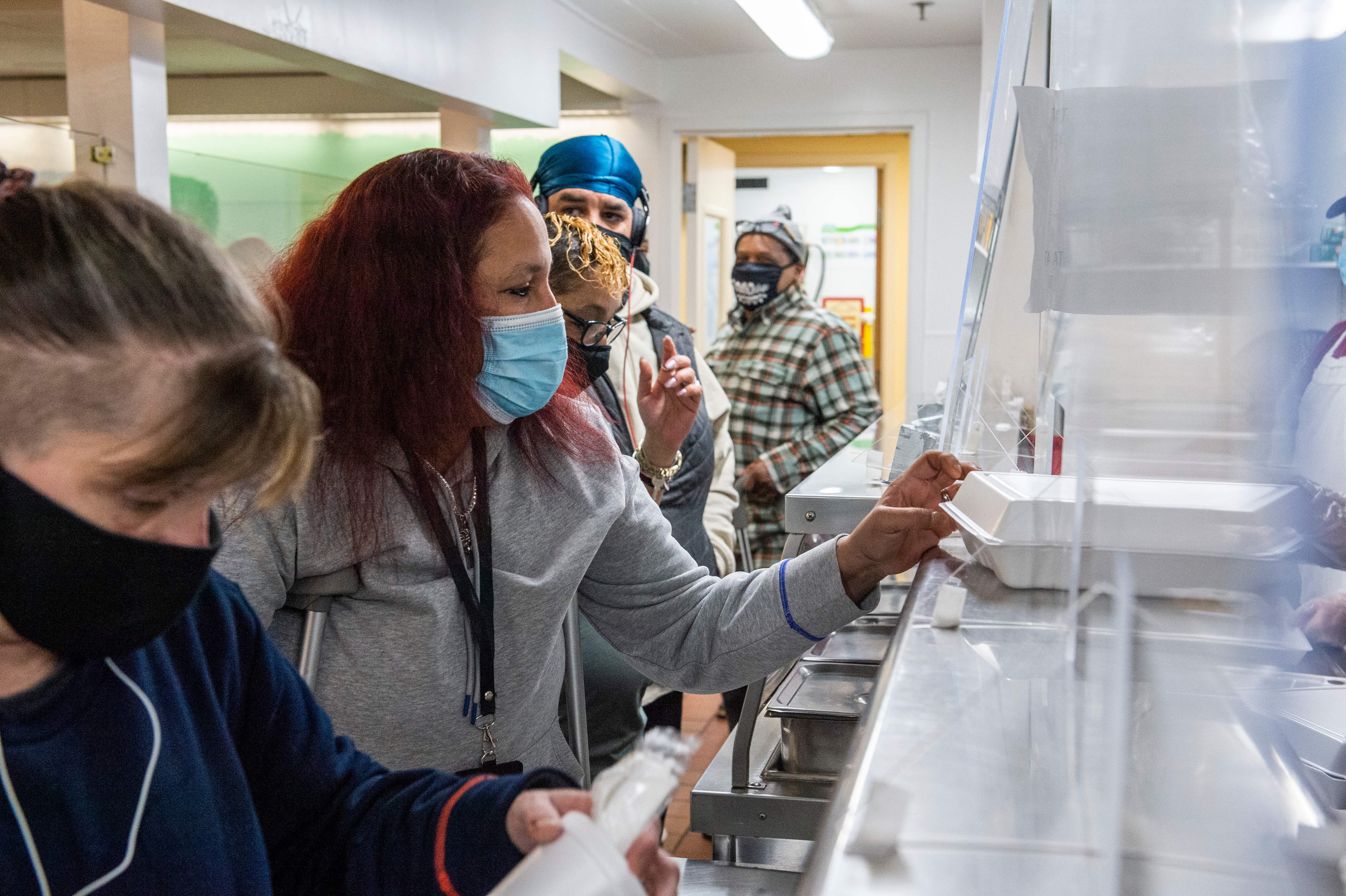 Volunteers serve a hot lunch to guests at the St. Francis House in Boston, Massachusetts on December 30, 2020. (Photo by Joseph Prezioso / AFP)