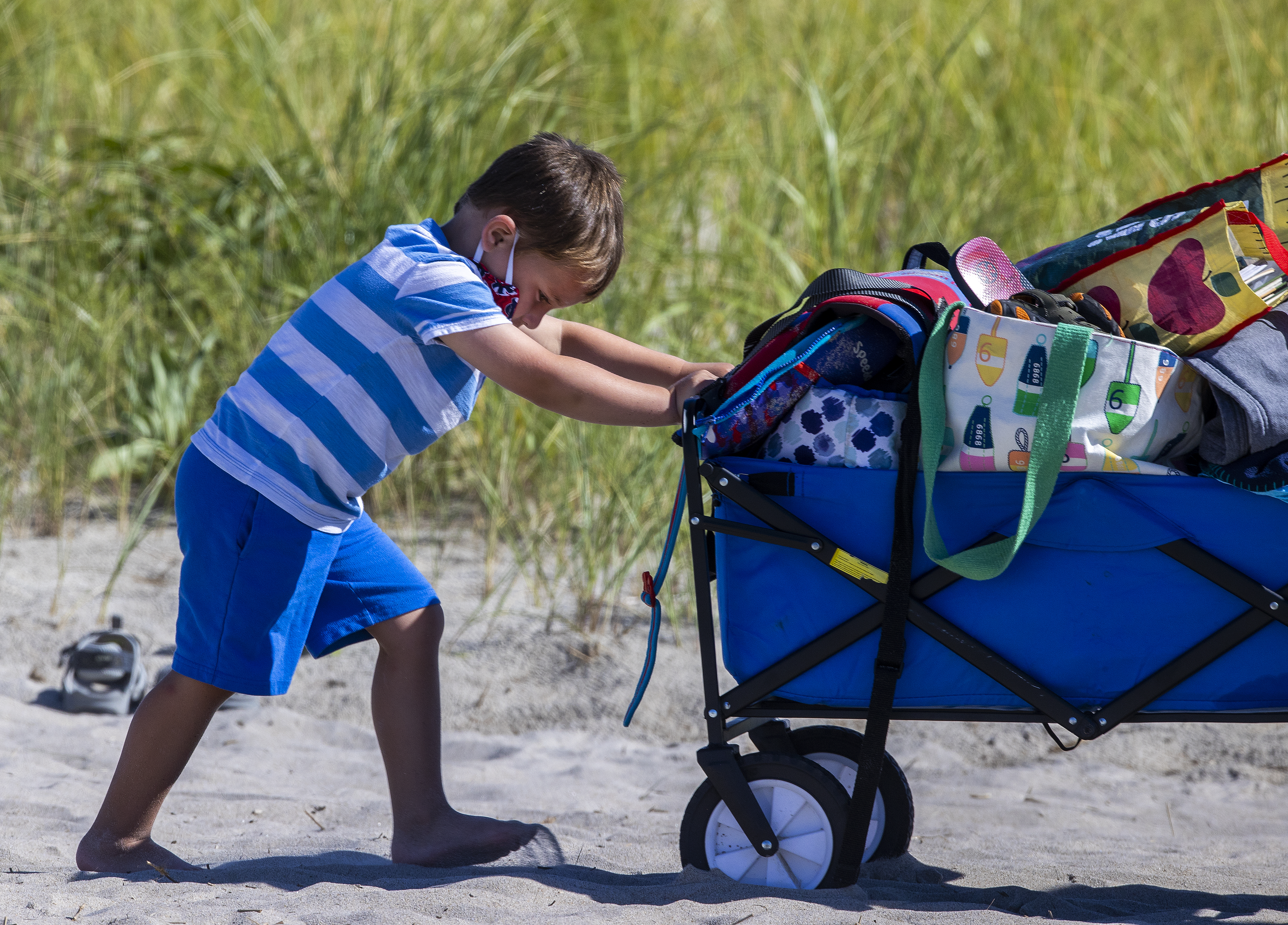 A boy helped his mother push the beach supplies as they left Crane Beach in Ipswich.