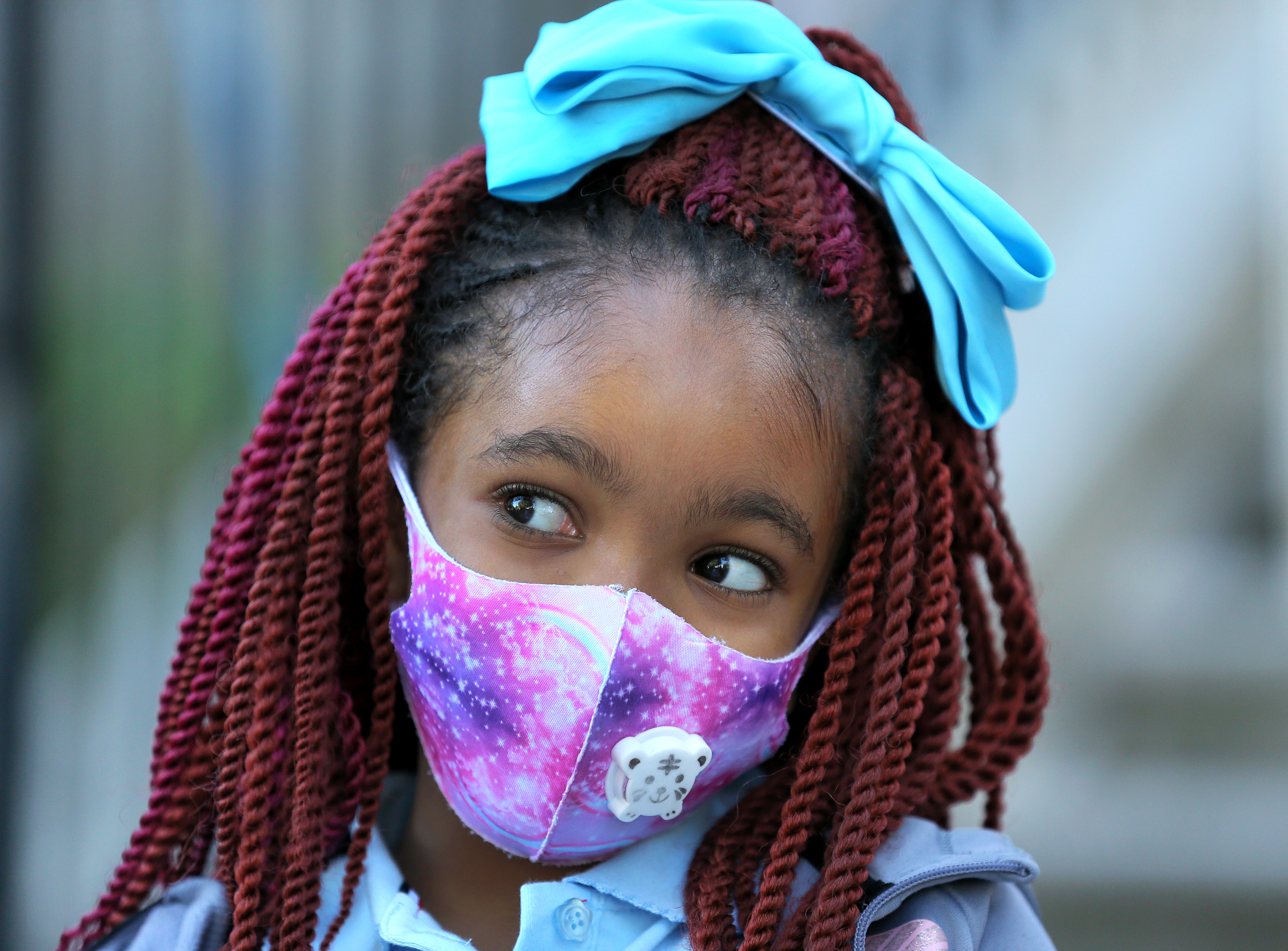 Wearing her mask and a bow in her hair is Esther Aguelar, a second grade student who returned to the Ellis Elementary School in Roxbury.
