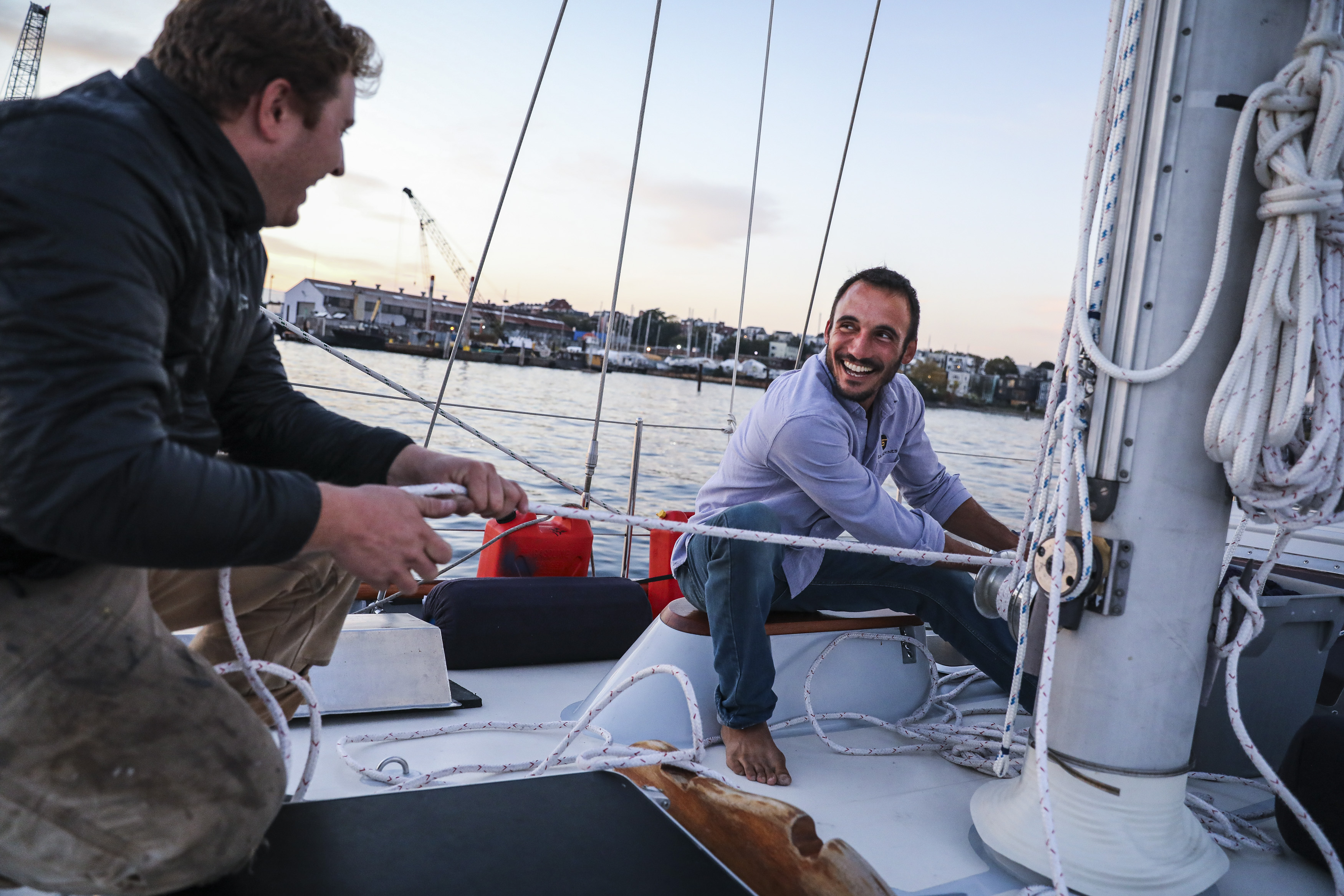 Mike Haith (left) helped Galdo pull out the sail on Restless while it was moored in the harbor in East Boston.