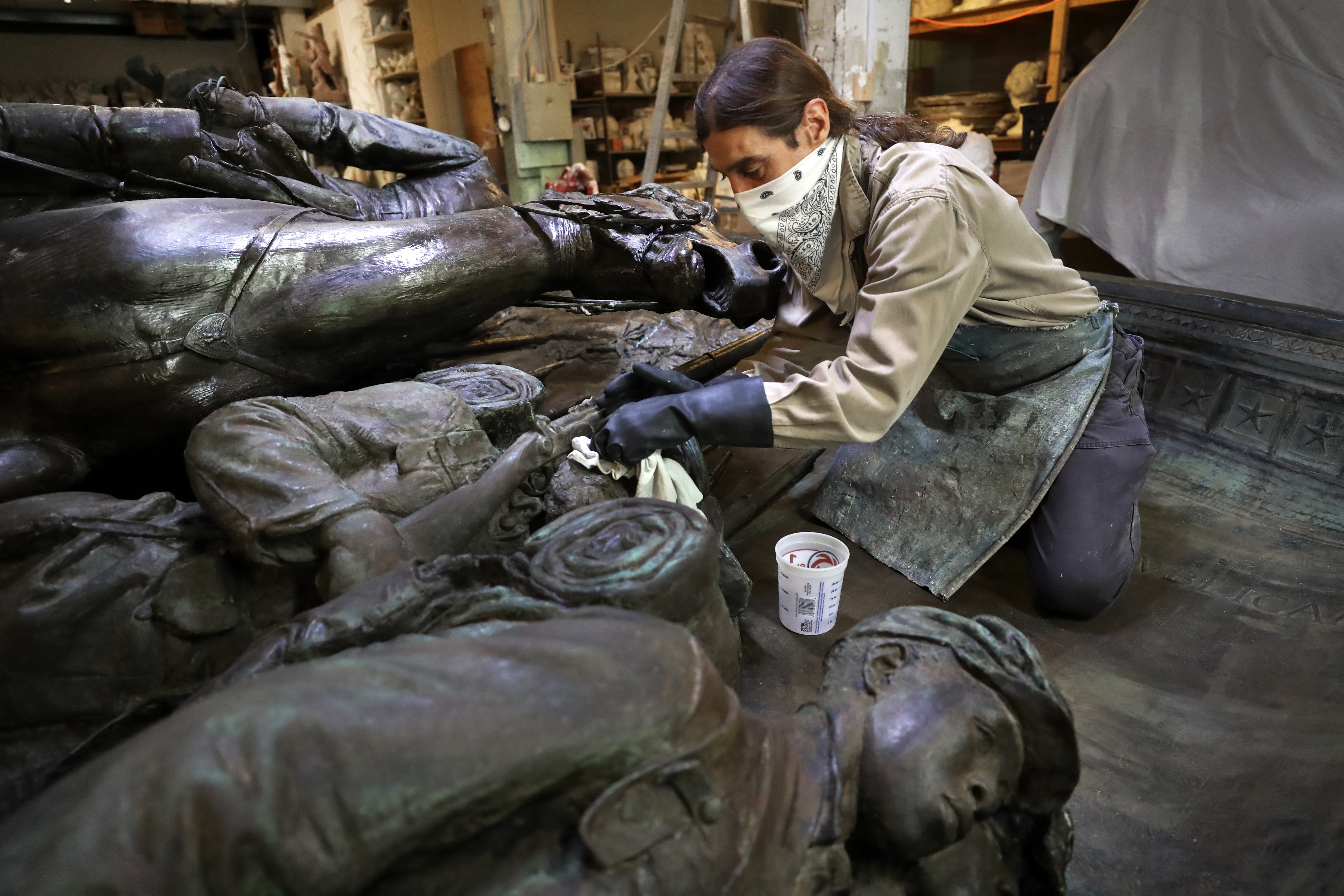 Martin Sylvester, an employee with Skylight Studios in Woburn, applies a stripper on the sculpture.