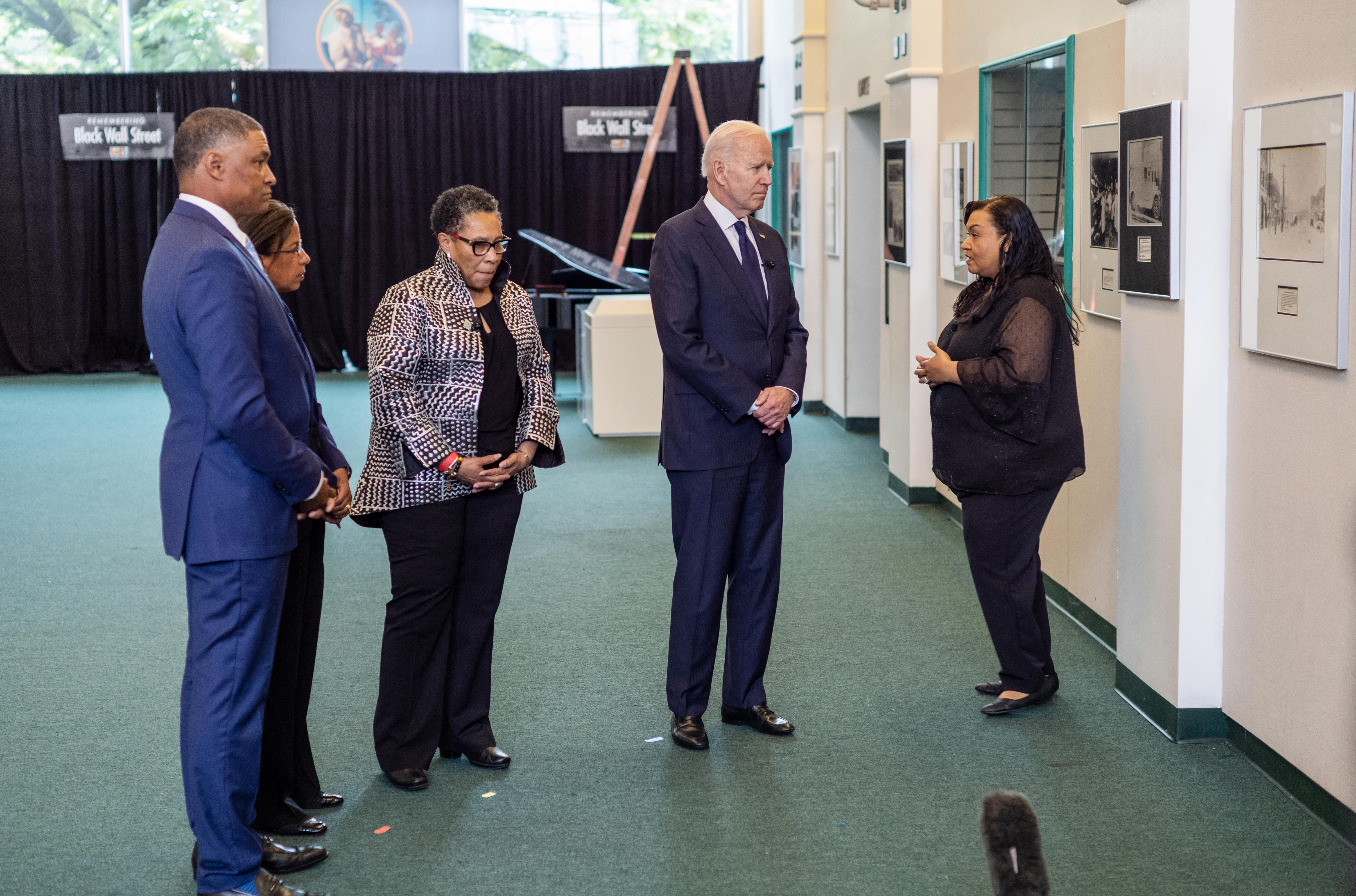 President Biden, second from right, with Urban Development Marcia Fudge, third from left, Director of the Domestic Policy Council Susan Rice, and Director of the Office of Public Engagement Cedric Richmond left, listens to Michelle Brown-Burdex, right, program coordinator of the Greenwood Cultural Center, as they toured the center in Tulsa, Okla.