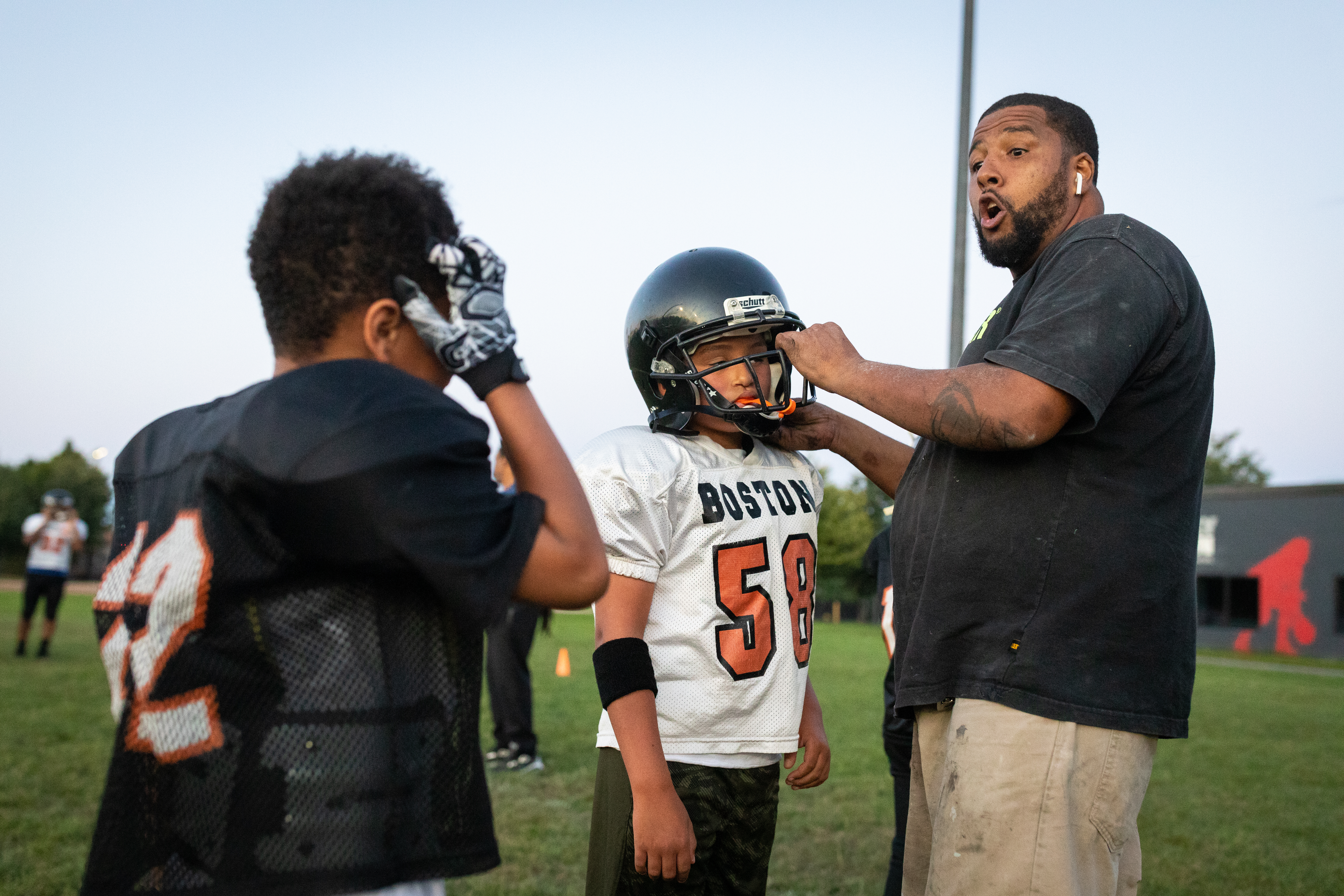Boston Bengals president Domingos DaRosa helped a player put on his helmet during team practice at Clifford Park on Sept. 3.