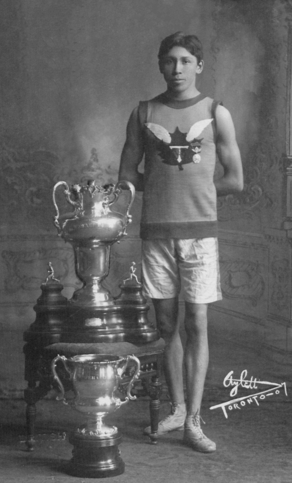 Tom Longboat, of the First Nations Onondaga, stands with trophies in 1907, the year he won the Boston Marathon.