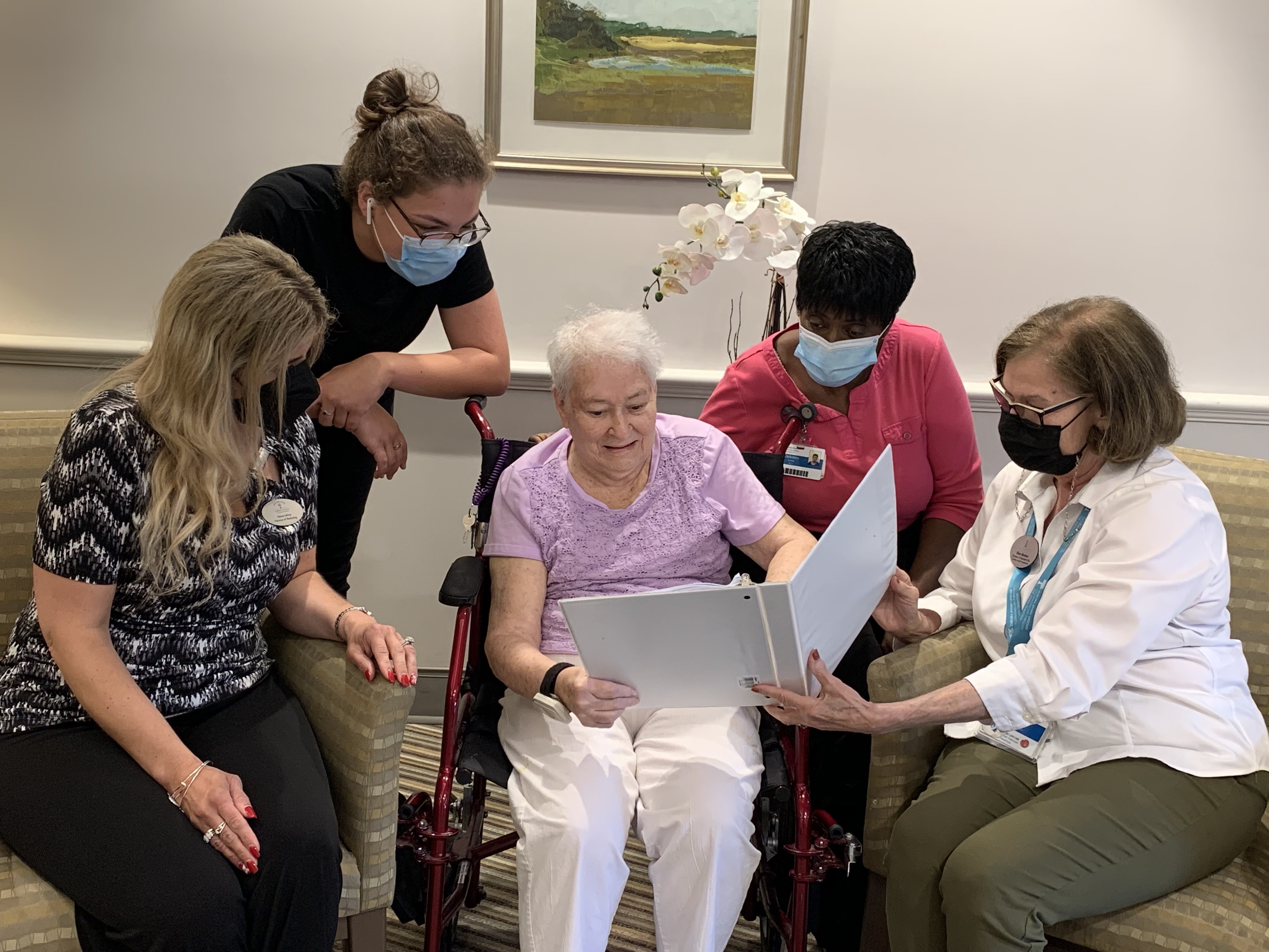 Kaplan Estates staff who helped orchestrate the wedding vow renewal ceremony looked at photos afterward with Alma Barrett, Judi Corbishley's mother. From left: Marisa Iafrates, Briana Williams, Barrett, Delores Lewis, and Ellen Gordon.