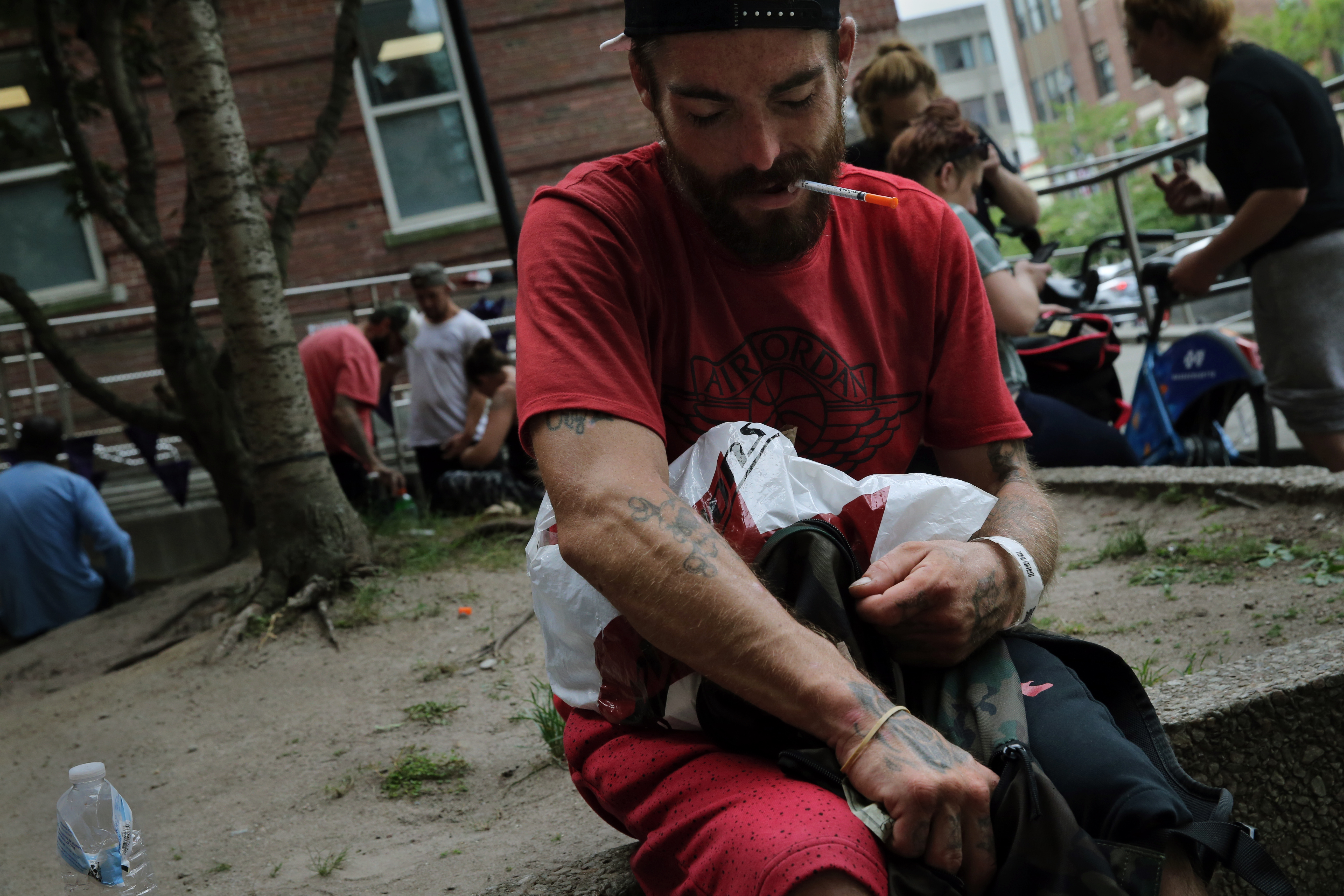 Stephen Smith held a needle in his teeth while sitting in a courtyard on Albany Street.
