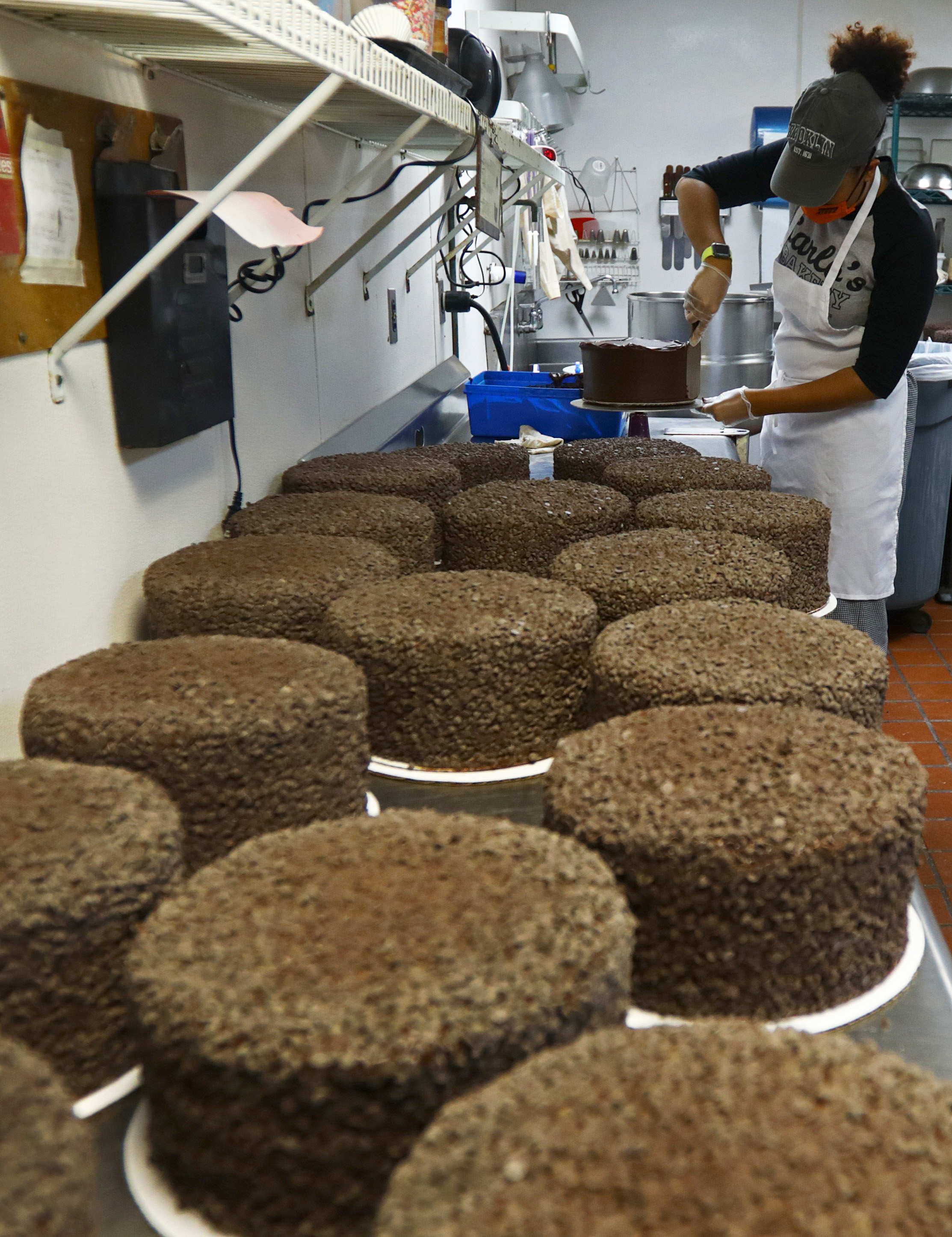 Cake finisher Nicole Morales frosts a six-layer “Death by Chocolate” cake at Gregg's in East Providence. For now, the pastry case appears fully stocked but supply chain issues are driving up prices.