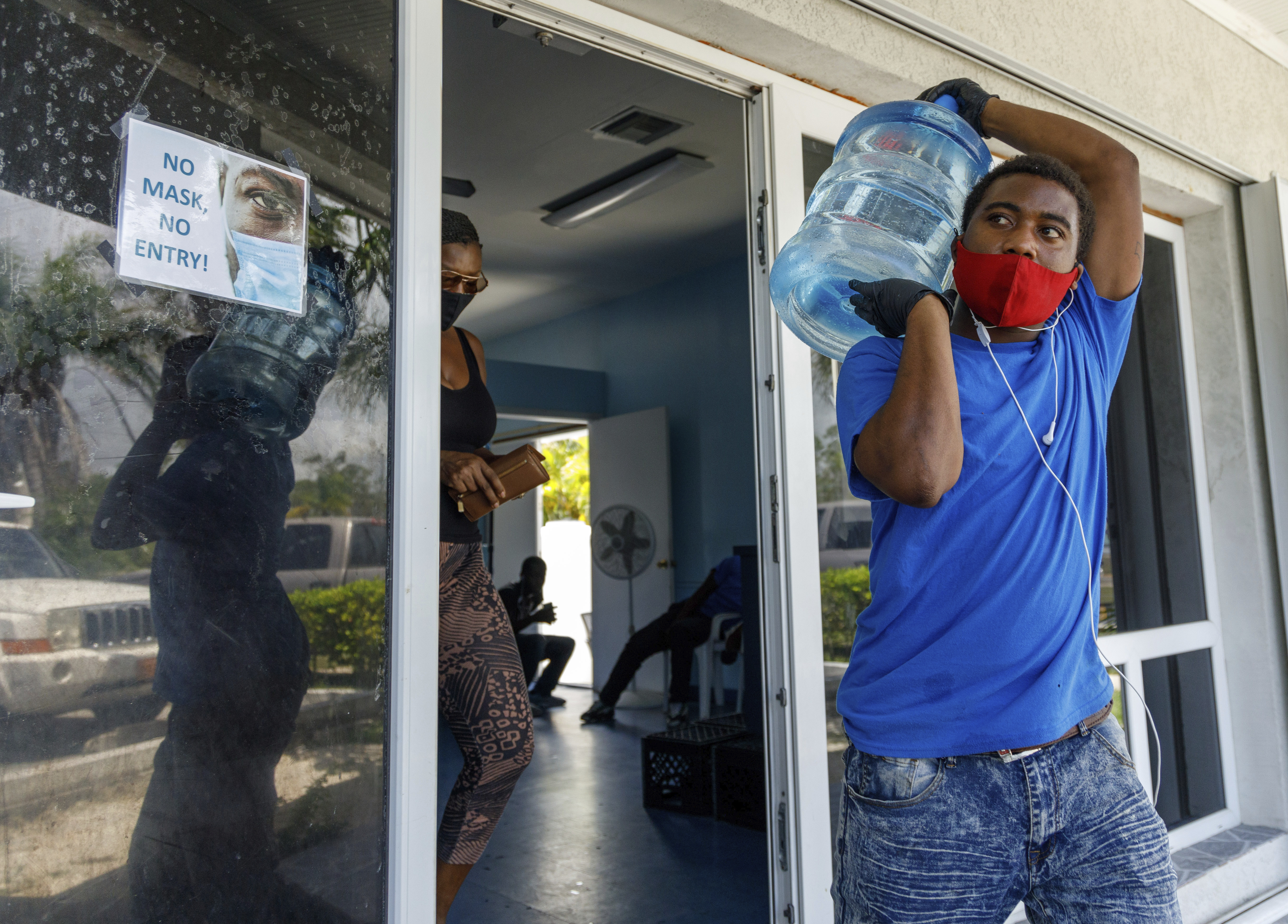 A man carried drinking water for a customer at a water depot store before the arrival of Hurricane Isaias in Freeport, Grand Bahama, Bahamas.