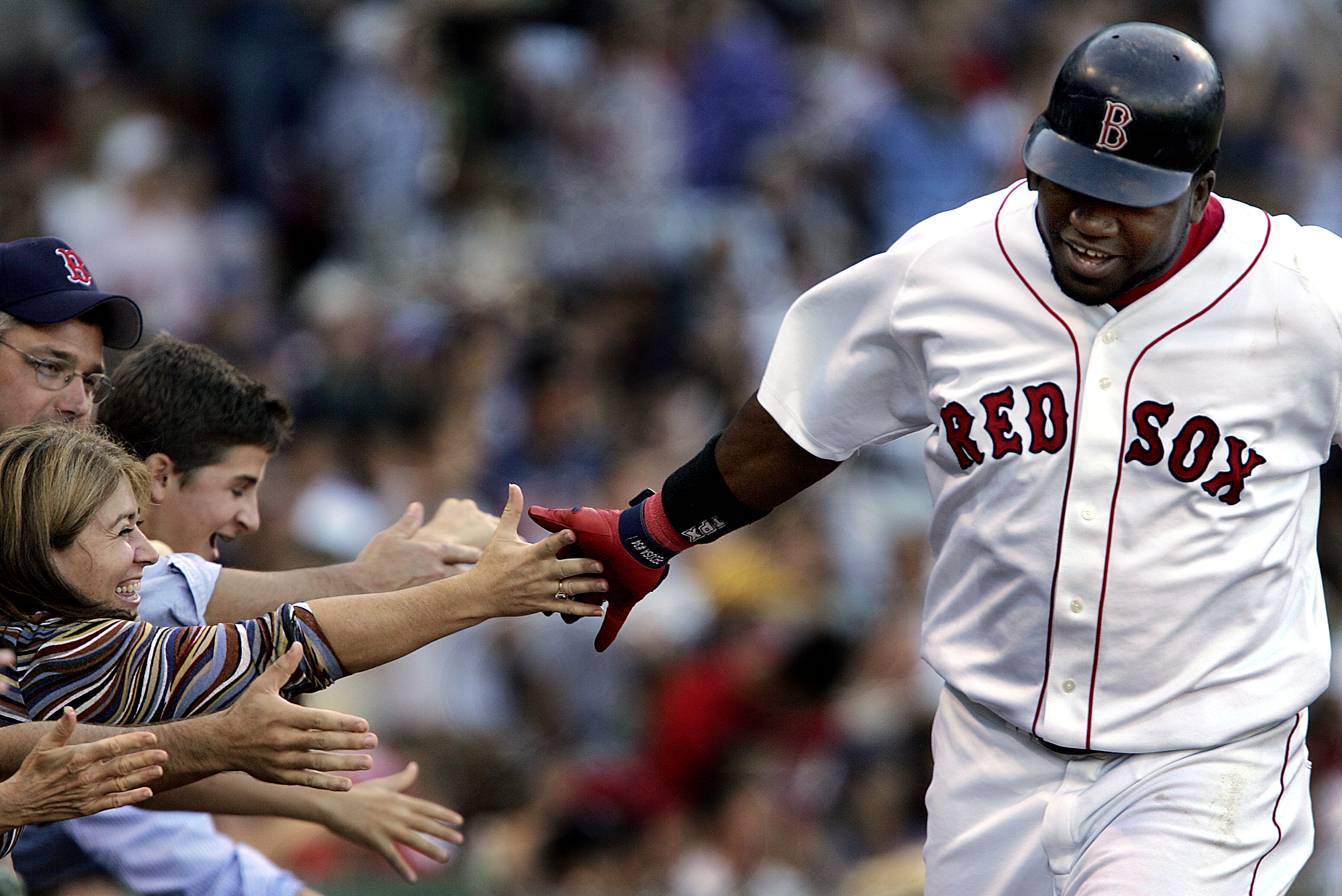 The Red Sox sold out every home game during the 2004 season en route to their first World Series title in 86 years. Here, Ortiz high-fives fans during the final regular-season game at Fenway Park that season, an 11-4 win over the Yankees.