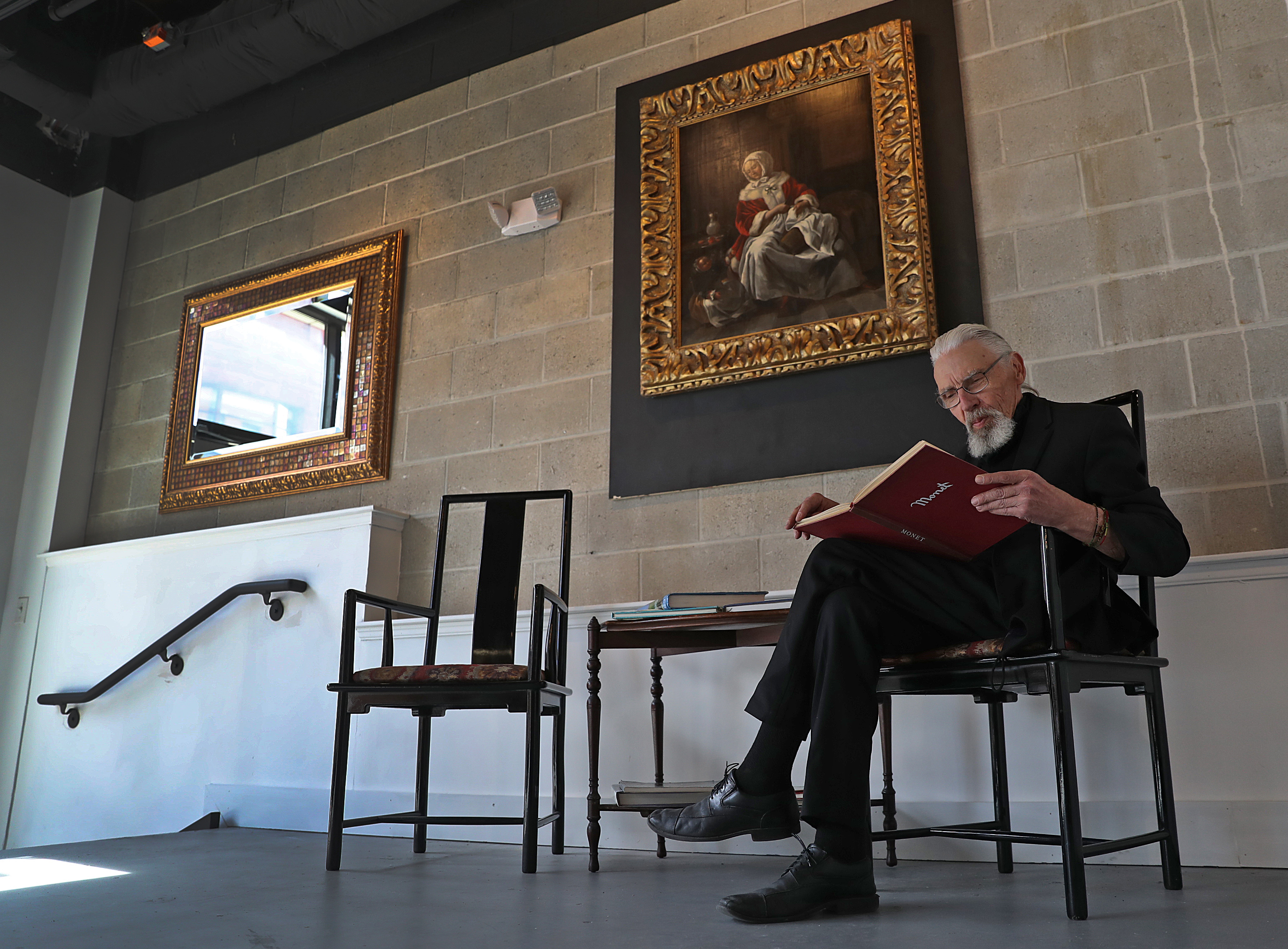 Milton Art Museum curator Arnie Danielson sat in the gallery with a book on Claude Monet.
