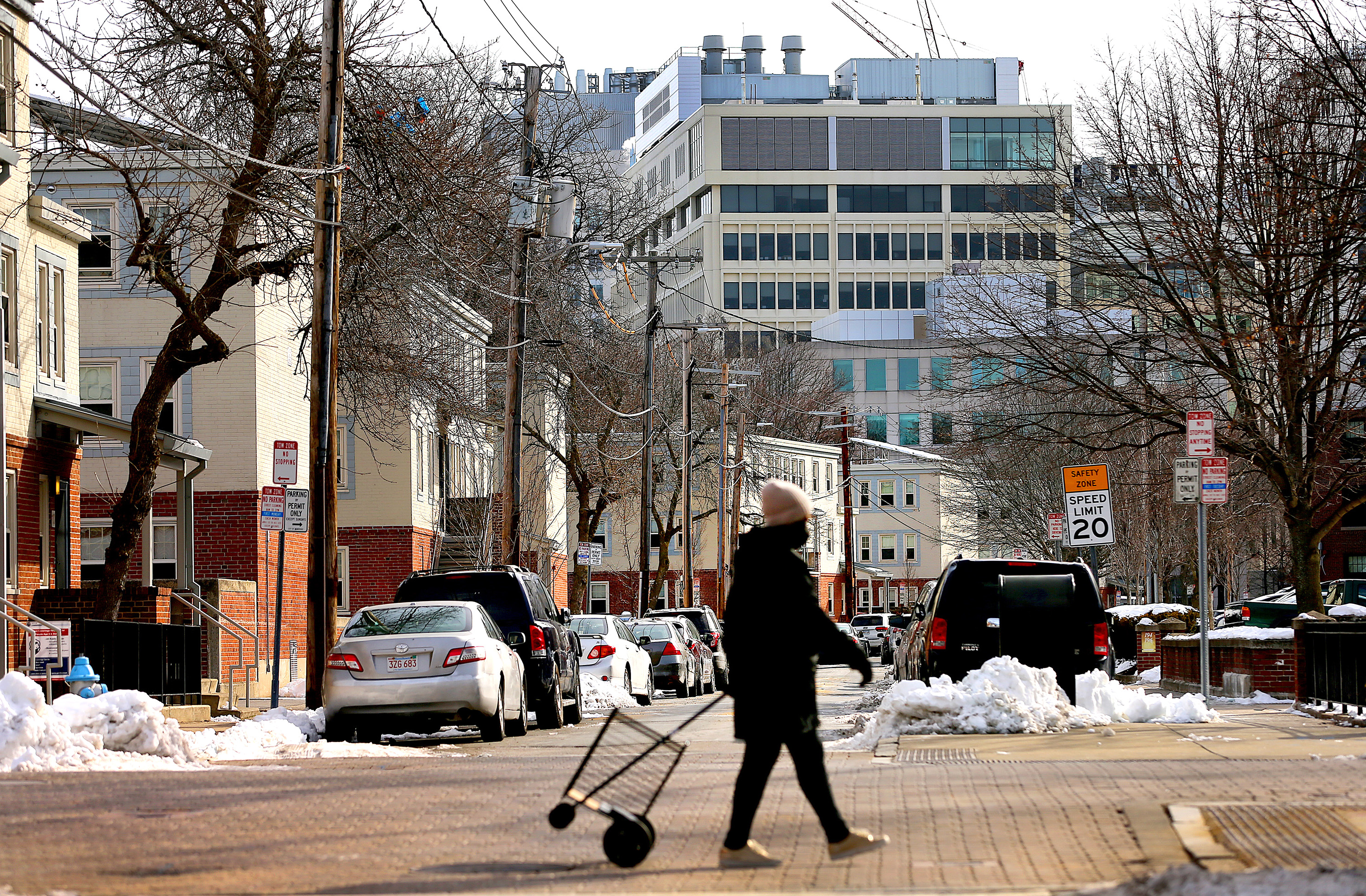 A woman walked by the Washington Elms Housing Development as highrise towers rise in Kendall Square nearby.