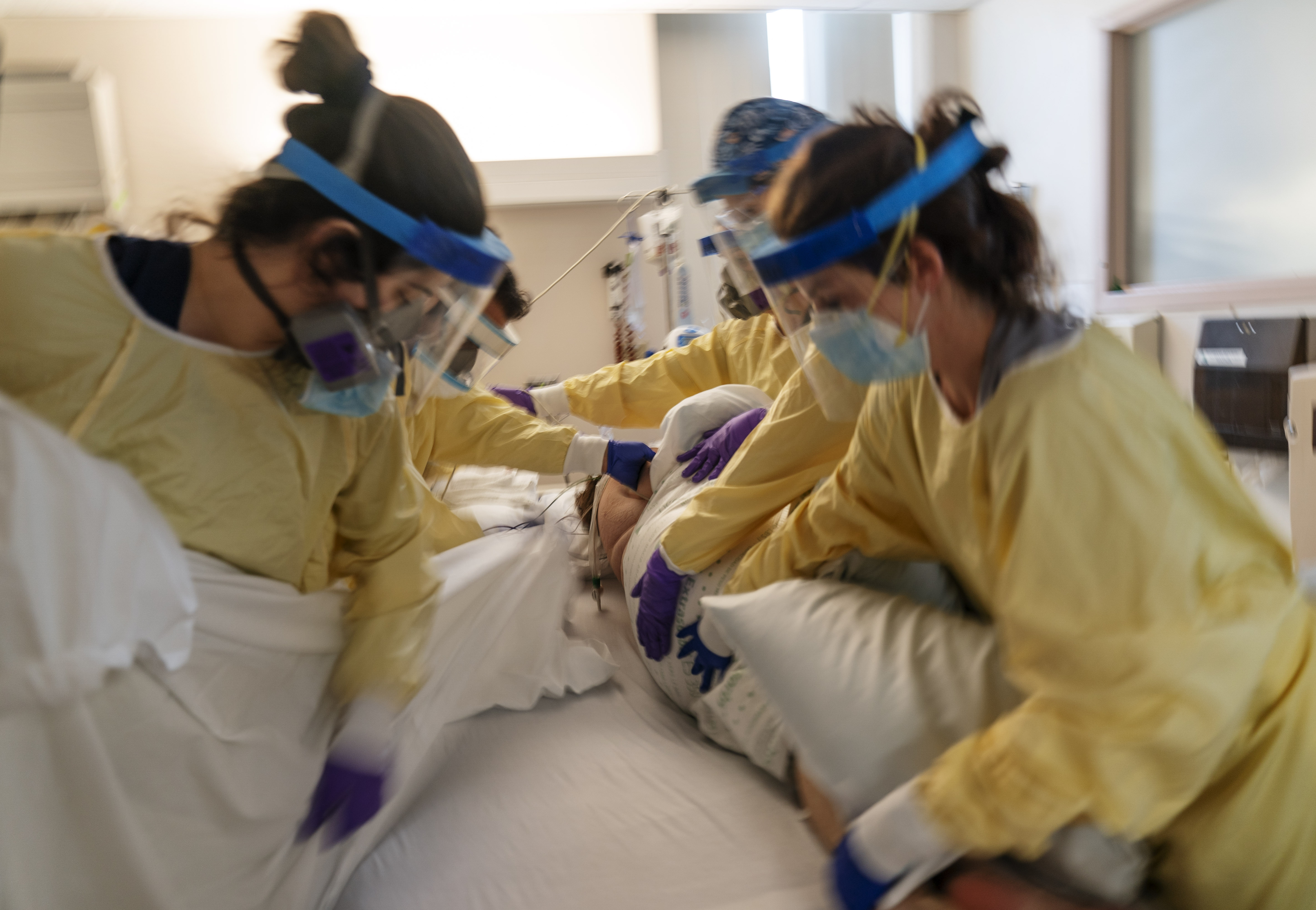 A medical team helps turn over a COVID-19 patient on a respirator onto the stomach to help with breathing inside the intensive care unit at Kent Hospital.