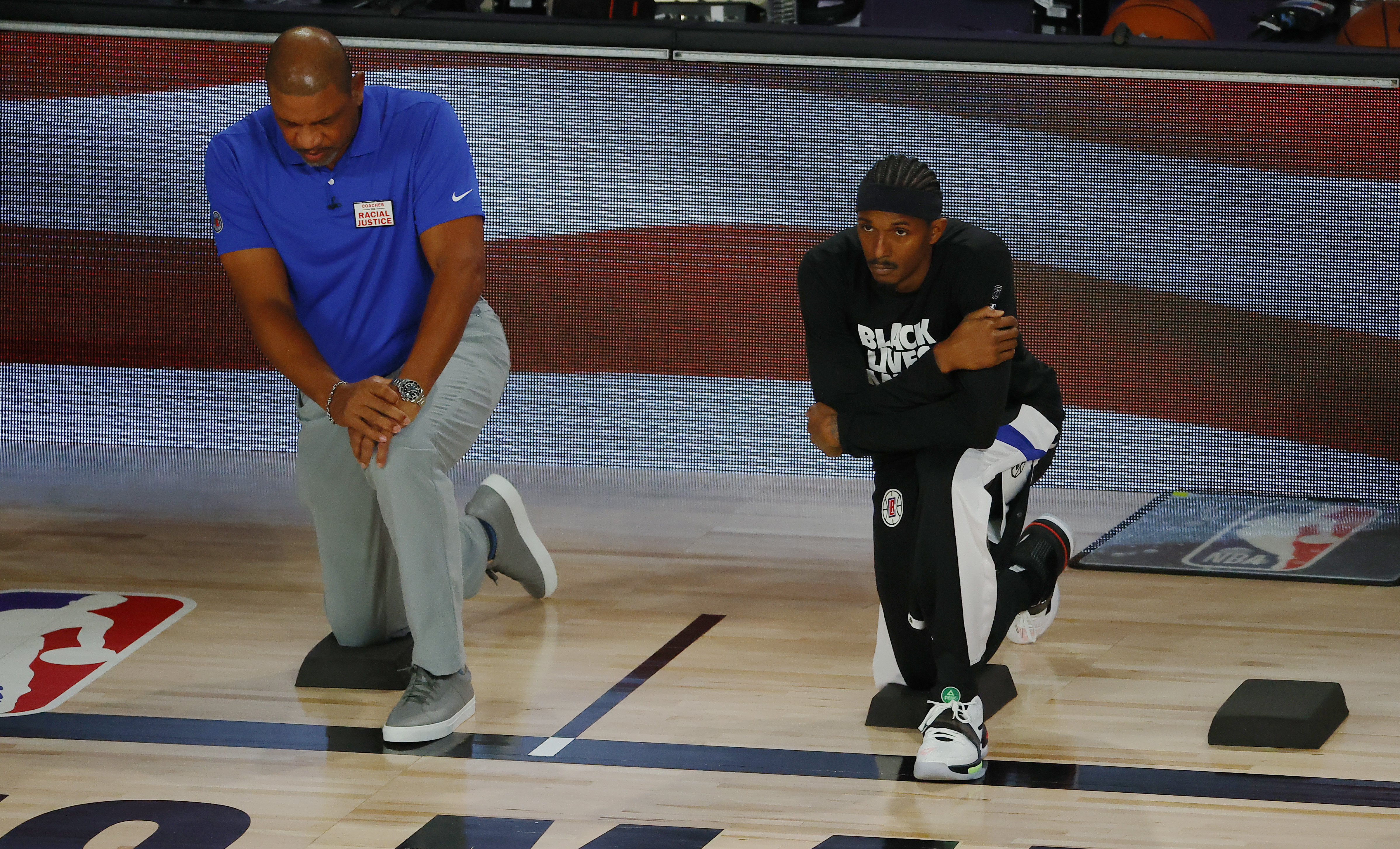 Doc Rivers and Lou Williams take a knee before an NBA playoff game on Aug. 23.