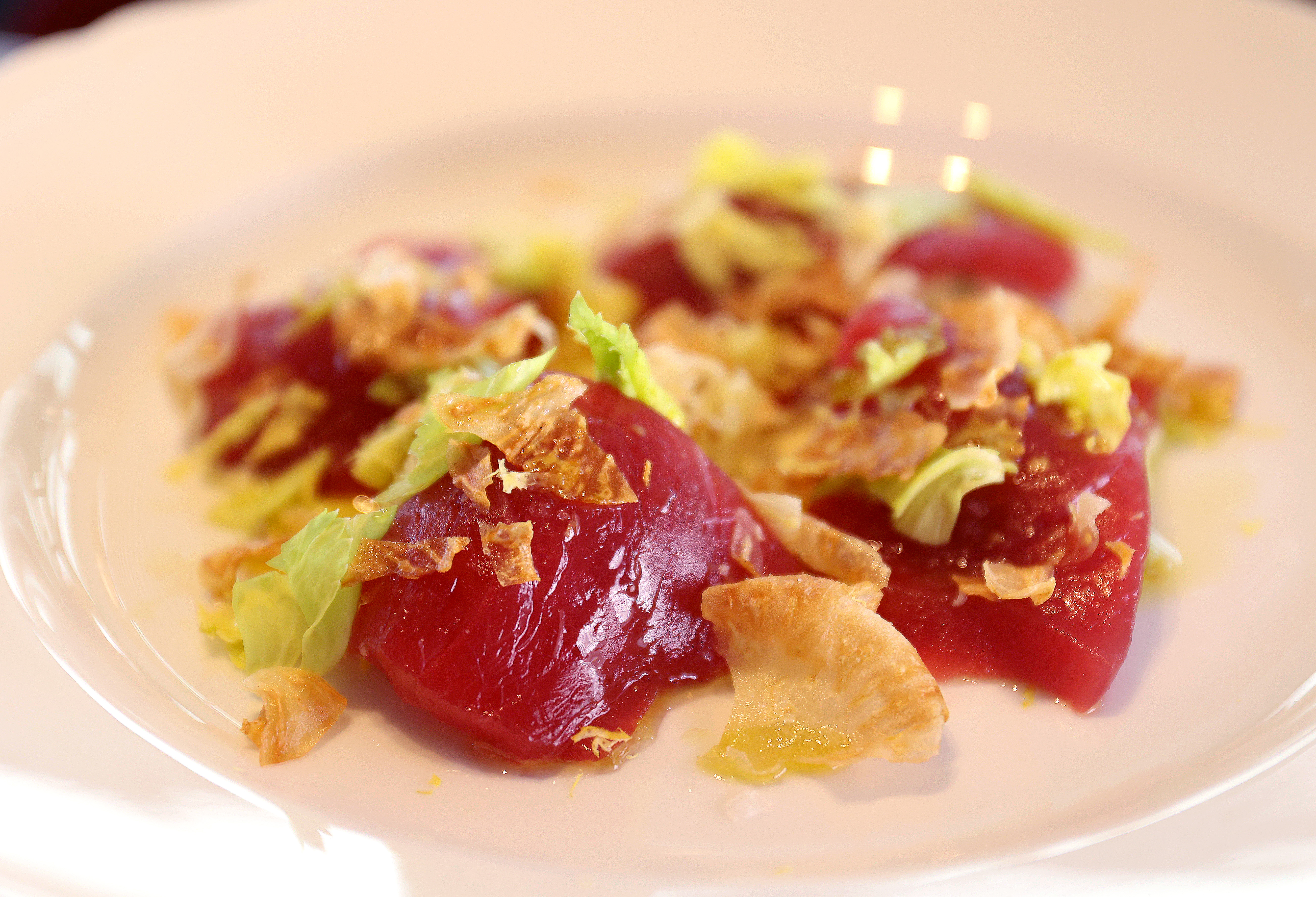 Tonnato crudo, a briny dish of thin-sliced raw fish over artichoke hearts with anchovy, capers, and celery leaves.