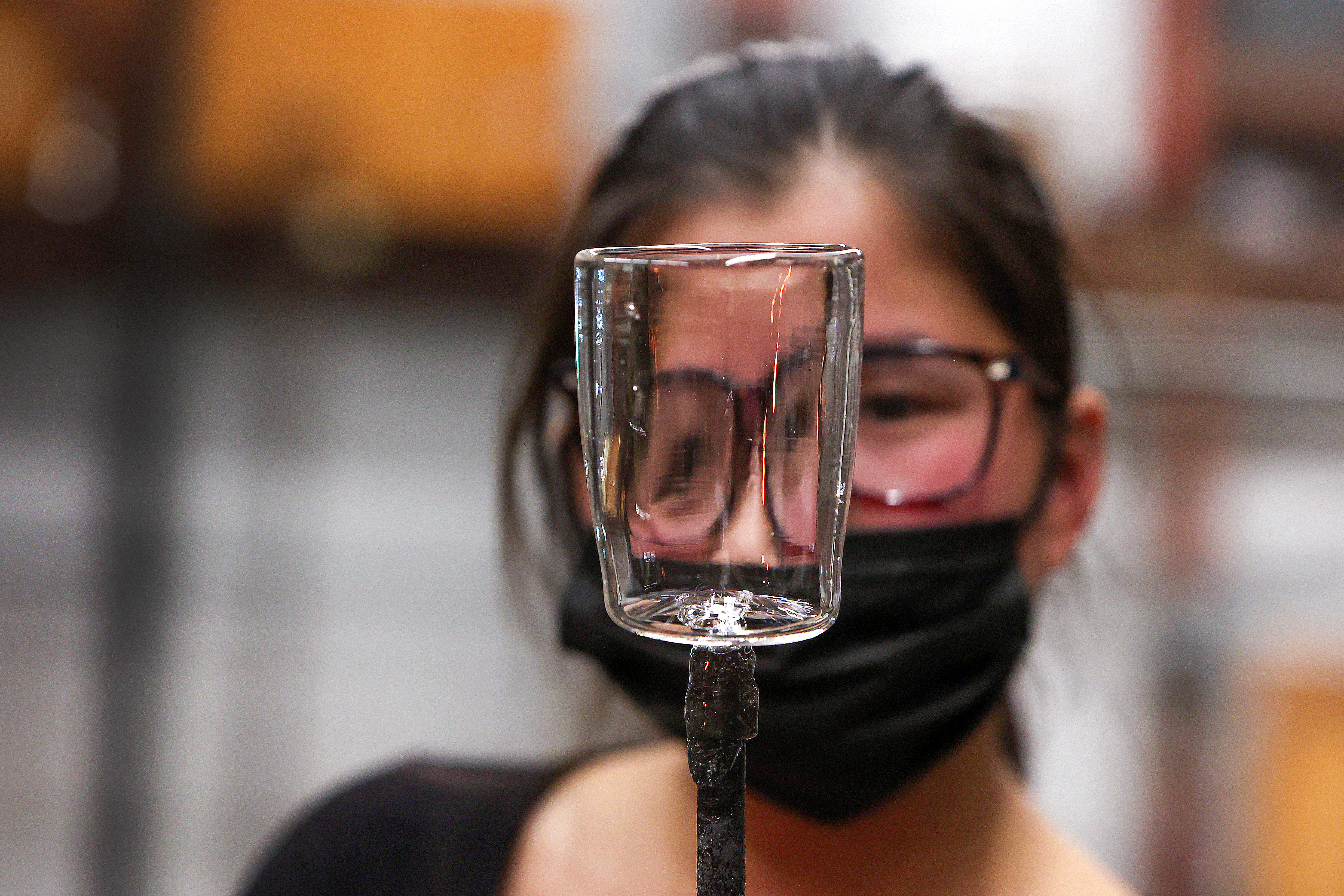 Celia Delani, glass and industrial design double major, looks at a finished glass mug in the glassblowing workshop.