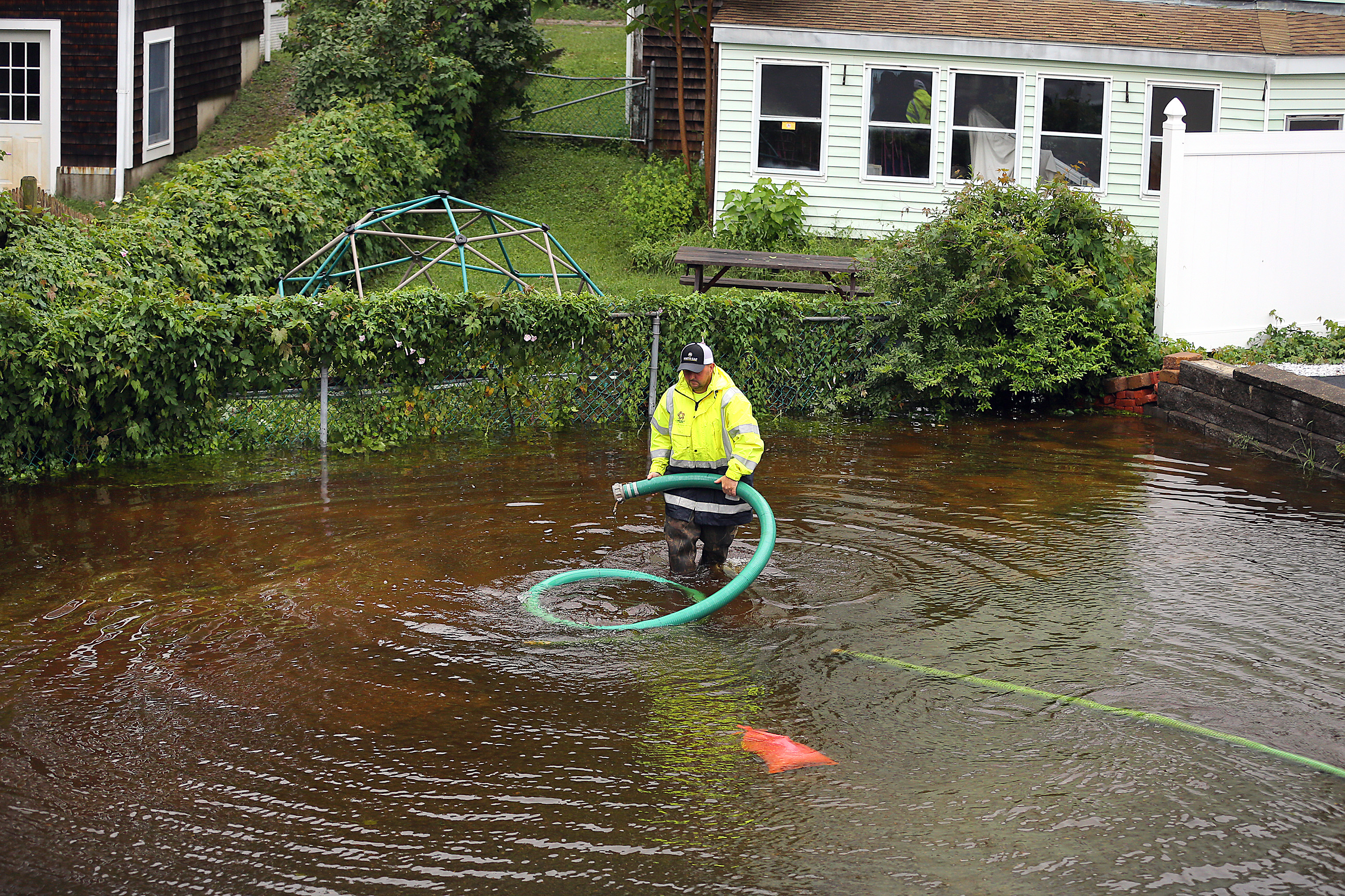 Plymouth Highway foreman Bob Birkenhead carried a large hose as he worked to pump out a flooded parking lot behind a beauty salon on Samoset Street in Plymouth.