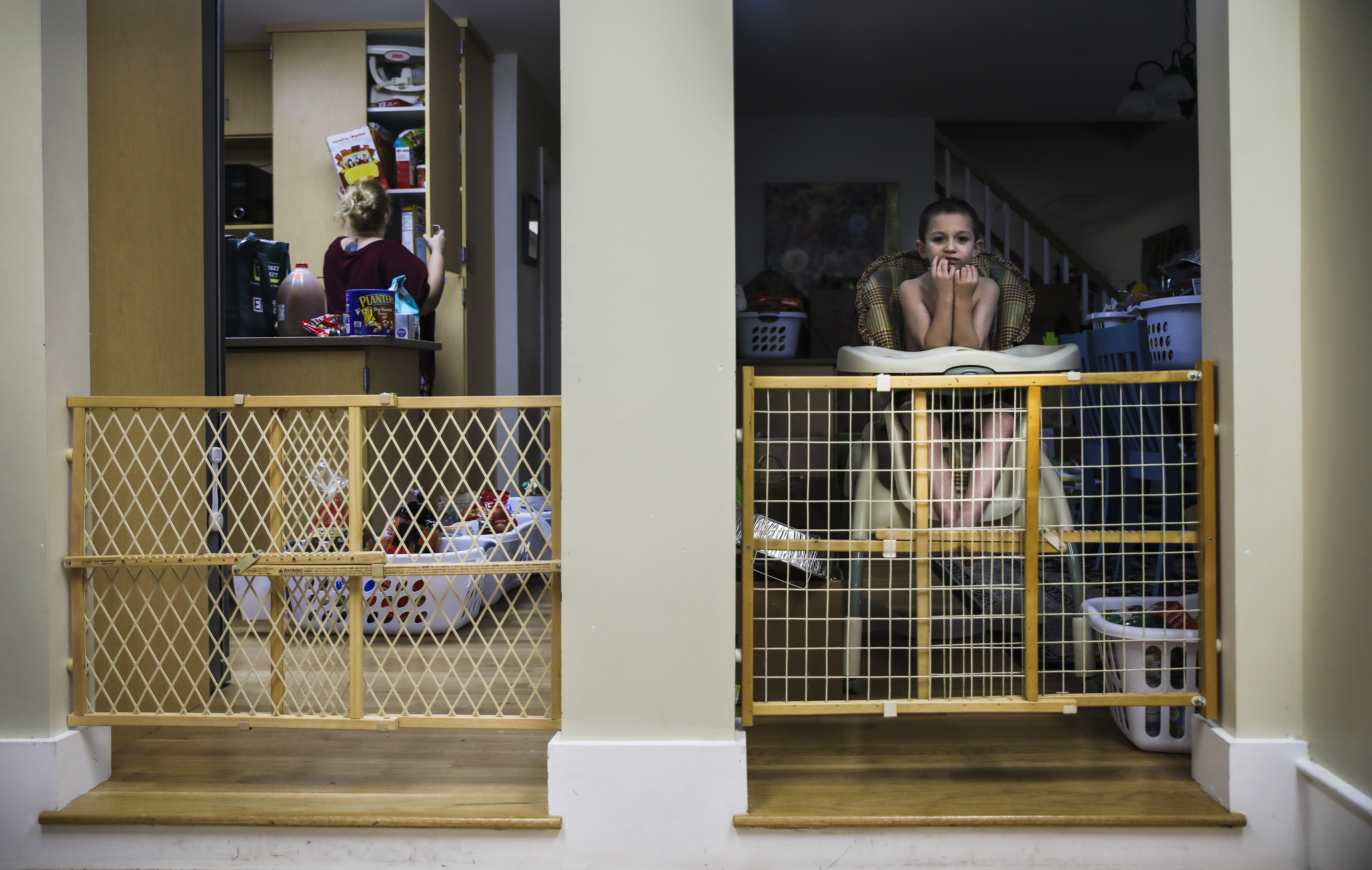 Mariah searches for after-school snacks at the Seacoast Family Promise day house while her son Dylan waits in a highchair. She uses the highchair to keep the 6-year-old, who has non-verbal autism, focused and stationary while eating. For three months, the family rotated through church shelter programs weekly for a place to sleep and eat.