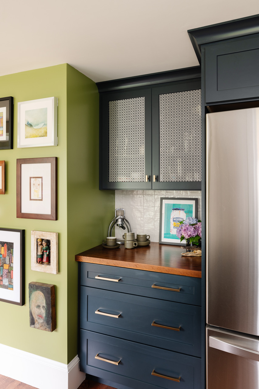 Inserts in the upper cabinets break up the blue and hide what’s inside. The gallery wall includes art from the couple’s travels.