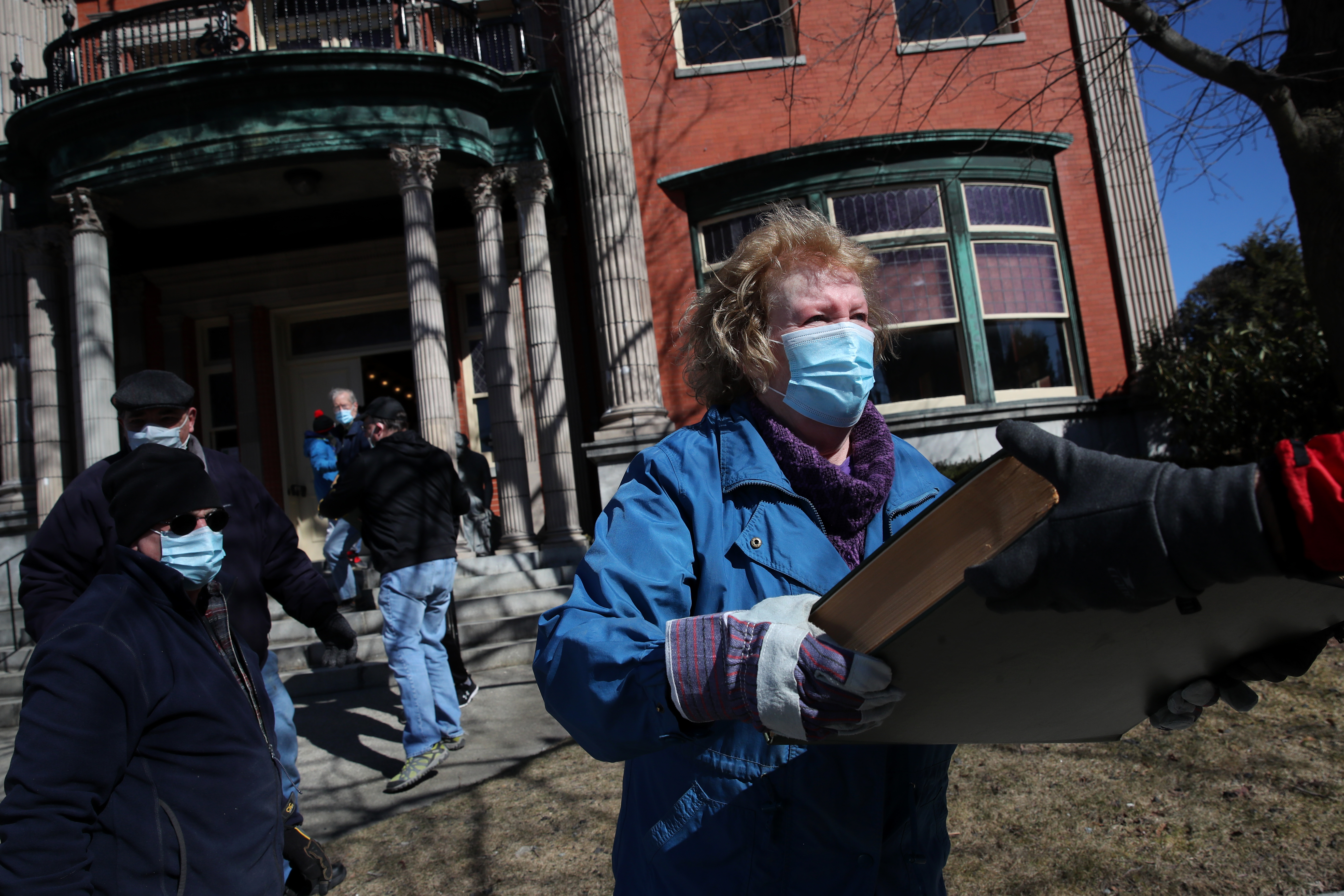 Debra McMahon-Cote joined volunteers passing volumes of the Clinton Daily into the Clinton Historical Society Item in Clinton.