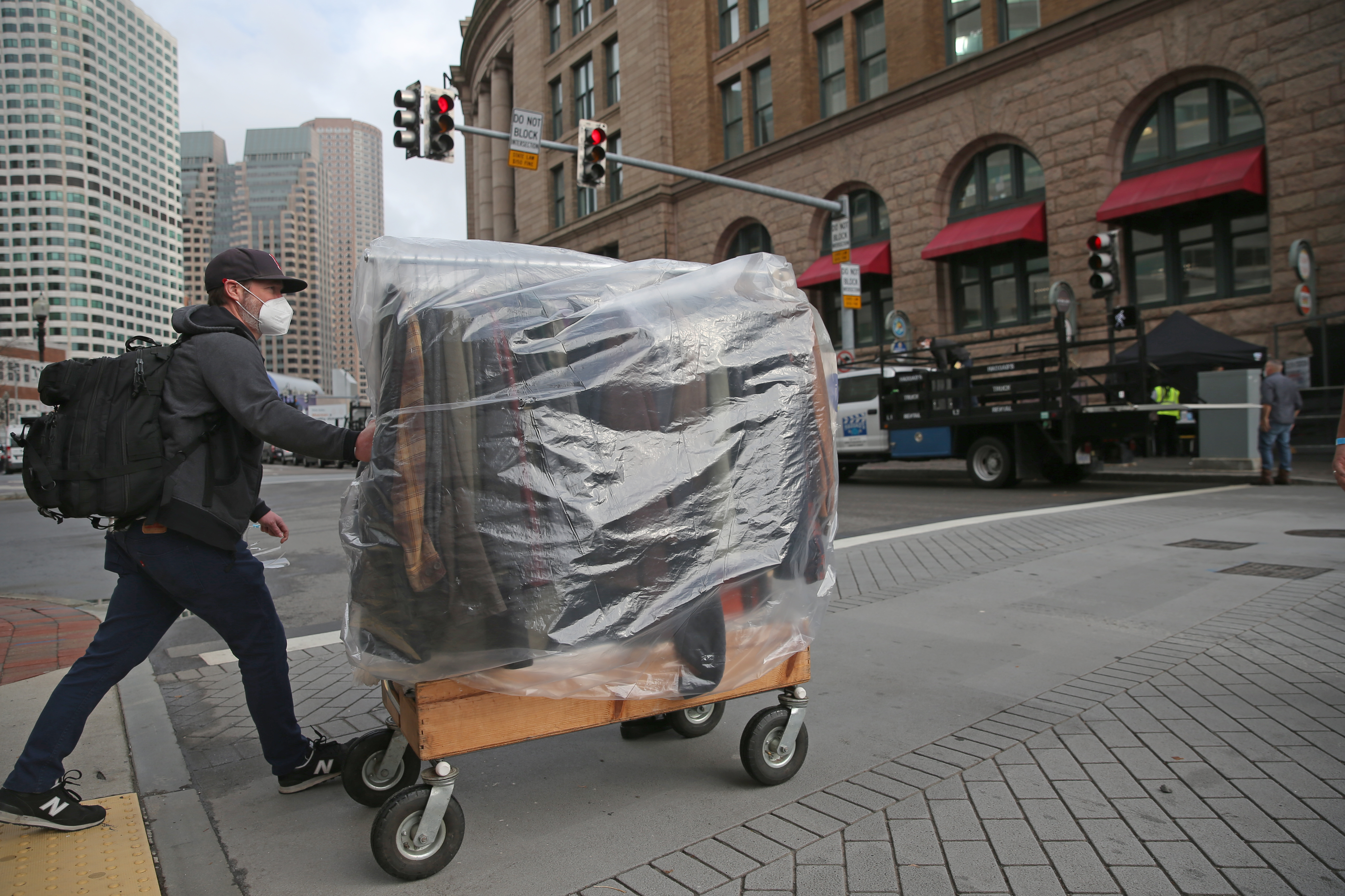 A film crew member rolled a wardrobe across the street towards South Station.