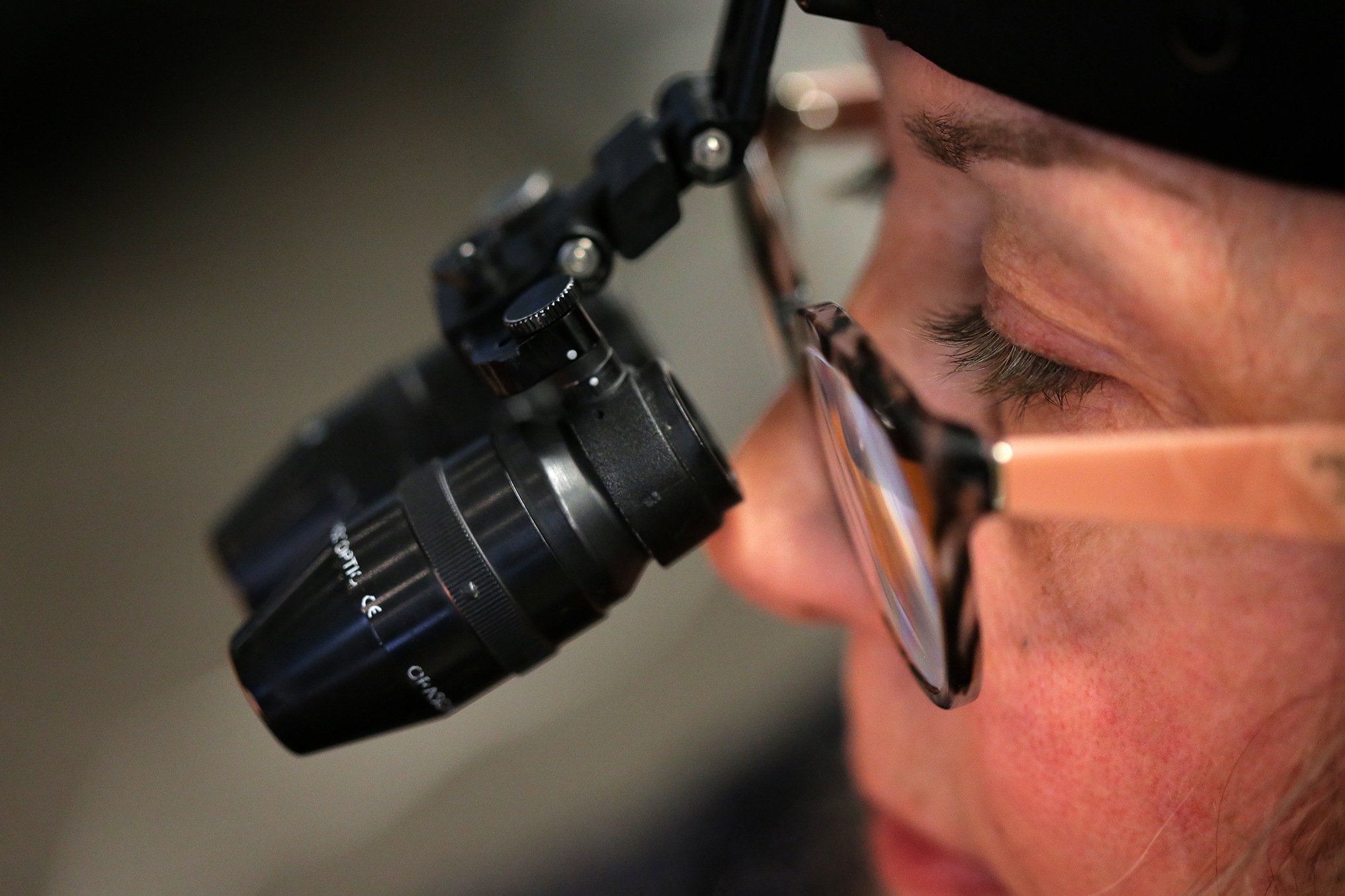 Toni Columbo uses a loupe to magnify her work.