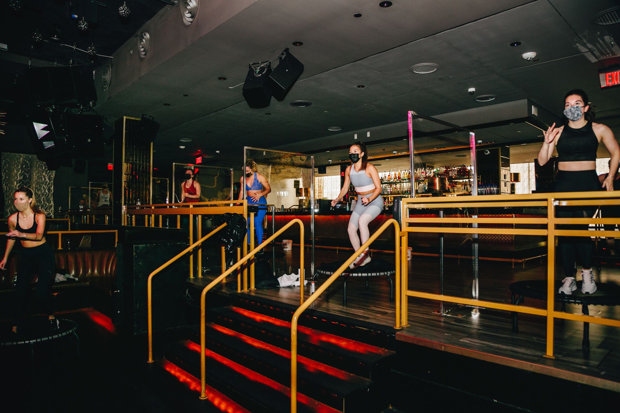 Participants in a Barre Groove class jump on trampolines in front of a bar at the Grand in the Seaport District, which remains closed as a nightclub.