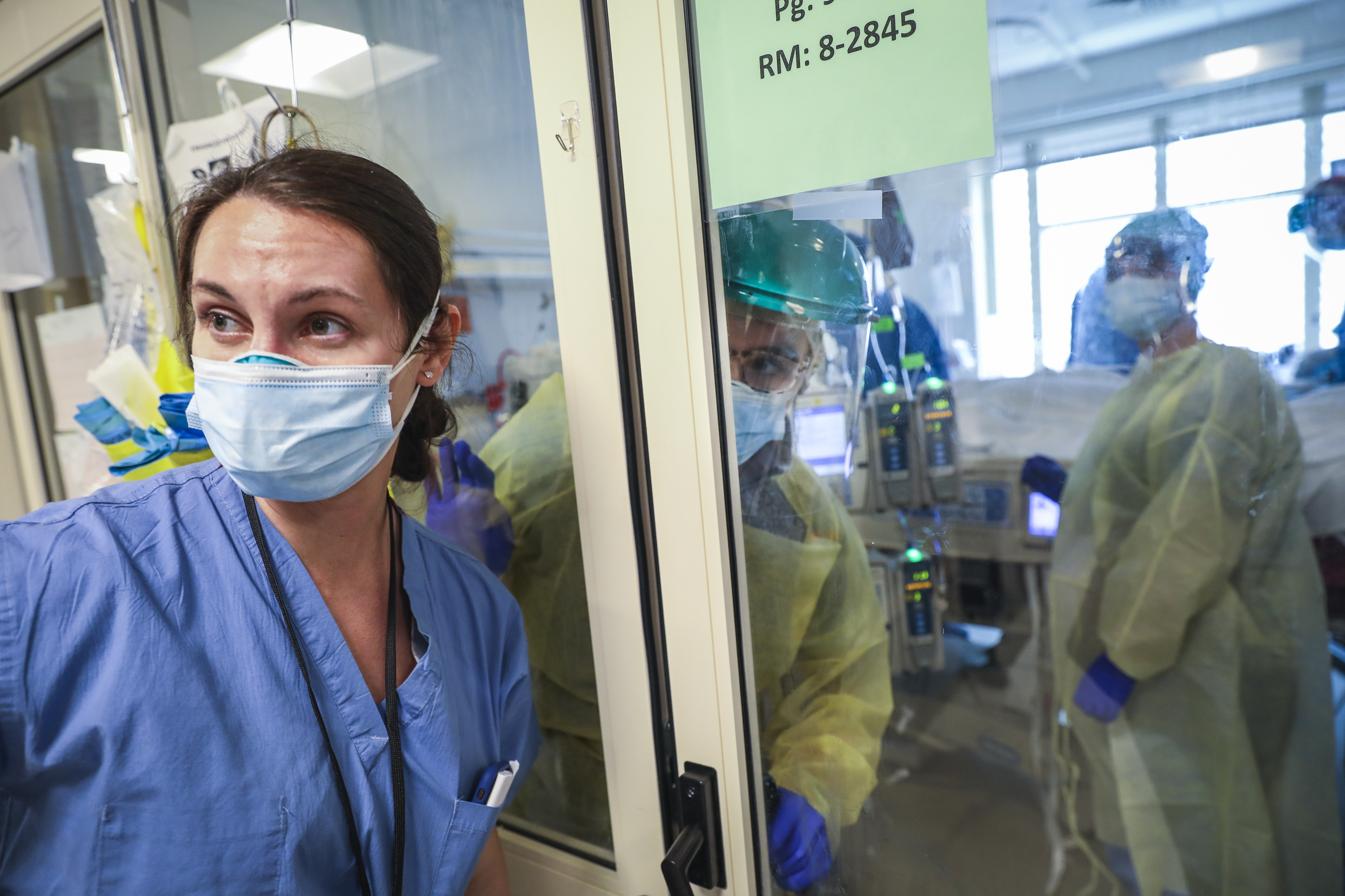 Respiratory therapists Mandi Britt (left) and Jaymee Moniz conferred through the glass doors of a COVID-19 patient's room during a procedure at Boston Medical Center. Only those with protective gear can enter the patient's room.